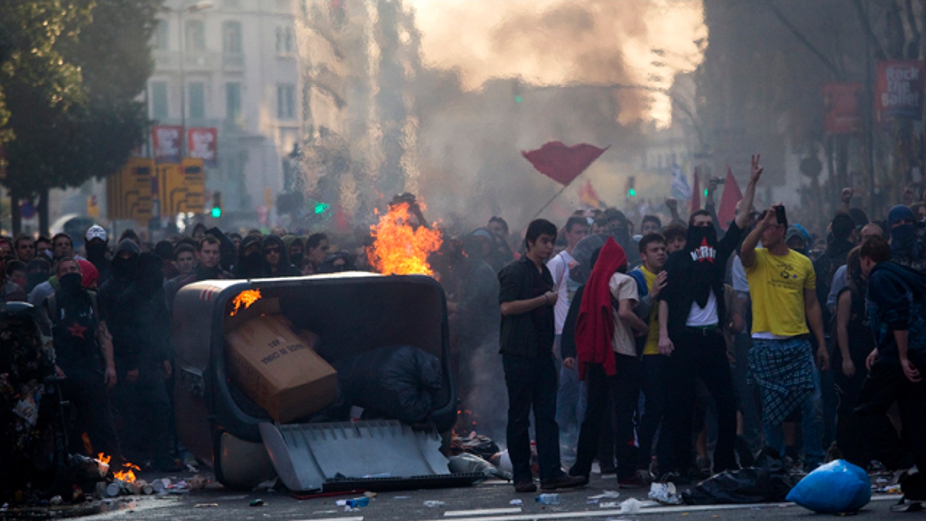 March 29, 2012: Demonstrators are seen next to burnt trash containers during clashes with police during a general strike in Barcelona, Spain.