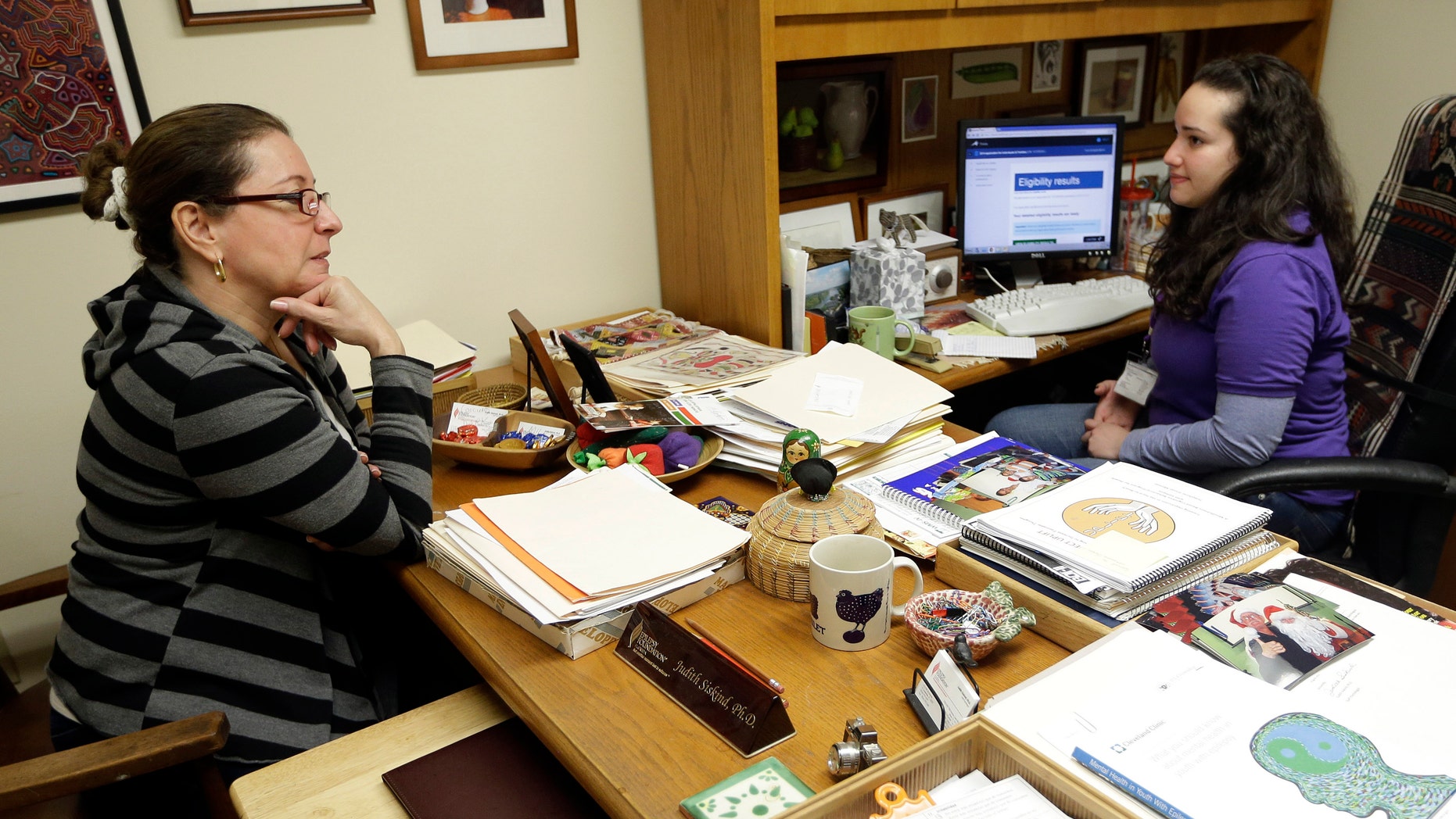 Yolanda Madrid of Miami, left, talks with navigator Daniela Campos, right, while signing up for health insurance under the Affordable Care Act, in Miami.