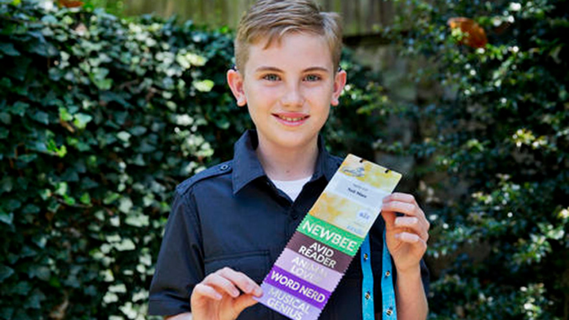 Neil Maes, 11, of Belton, S.C., holds up his National Spelling Bee badge at The Alexander Graham Bell Association for the Deaf and Hard of Hearing (AG Bell) in Washington, Tuesday, May 24, 2016.