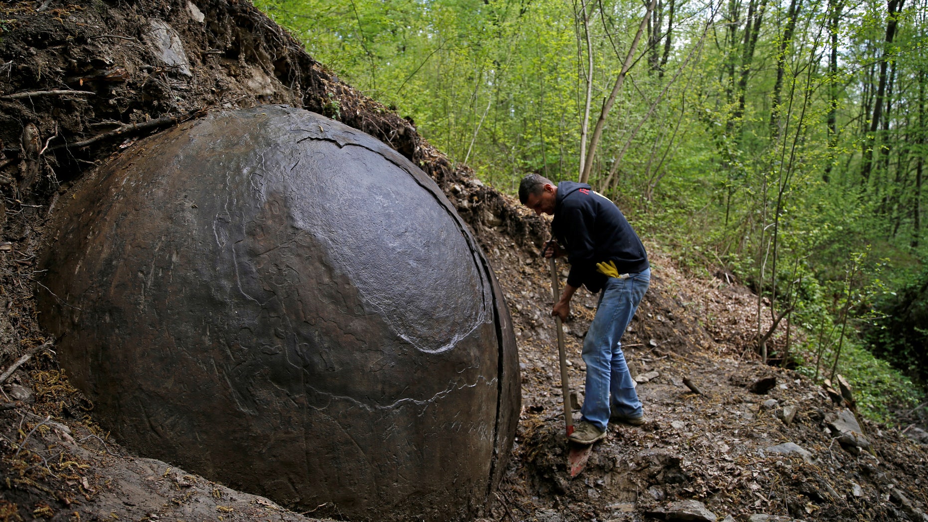 Suad Keserovic cleans a stone ball in Podubravlje village near Zavidovici, Bosnia and Herzegovina April 11, 2016. Keserovic claimed that the stone sphere is 3.30 meter in diameter and the estimated weight of it is about 35 tons. (REUTERS/Dado Ruvic)