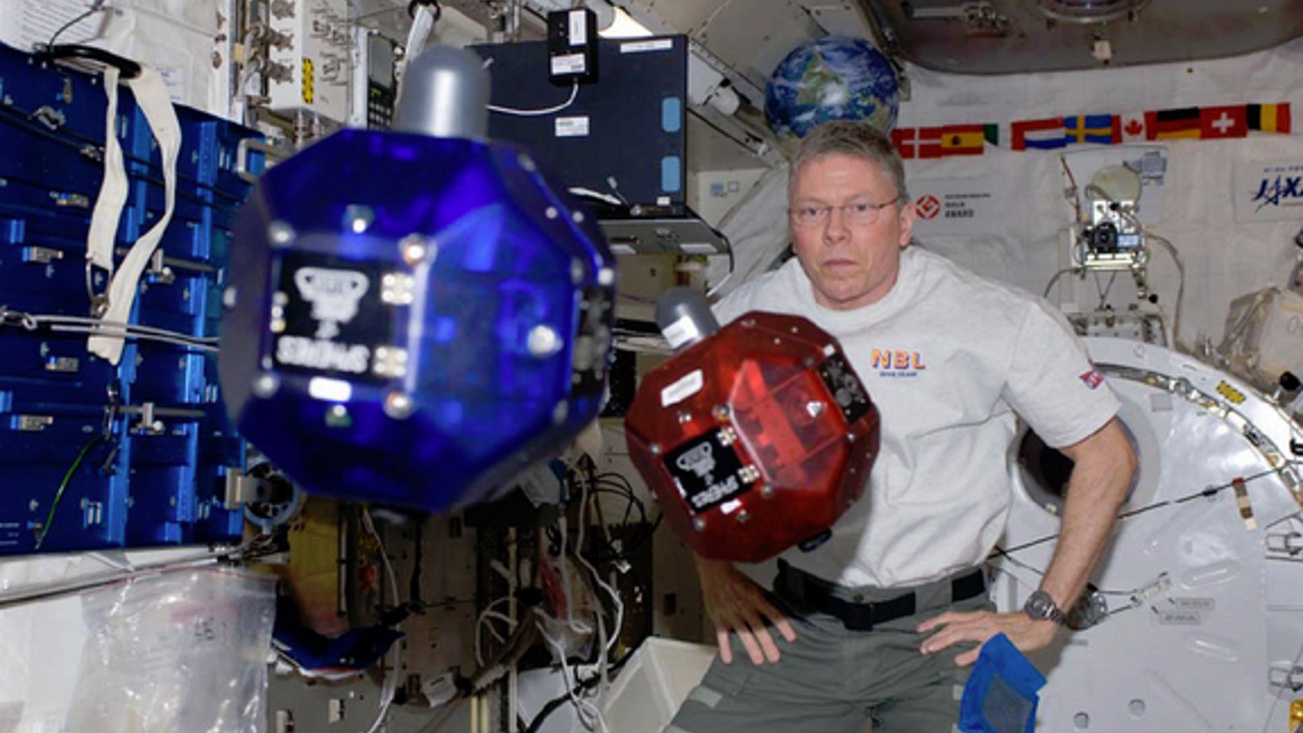 NASA Astronaut Mike Fossum operates small, autonomous satellites aboard the International Space Station in November 2011. Every year, high school students compete to submit computer code to run in the satellites, called SPHERES.