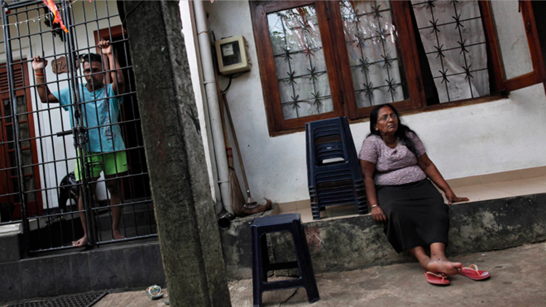 May 7, 2012: Ravindra Udayashantha, left, a 38-year-old town council chairman looks through iron bars guarding the entrance to his house, as his mother Rupawathi Perera sits outside in Kolonnawa, suburb of Colombo, Sri Lanka.