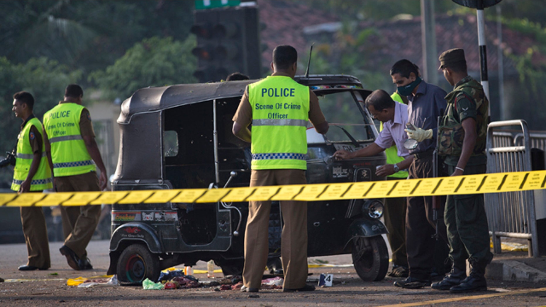 Nov. 10, 2012: Police forensic officers examine a bullet-ridden three-wheeled vehicle used by inmates for their unsuccessful escape attempt, close to the entrance of a prison in Colombo, Sri Lanka.