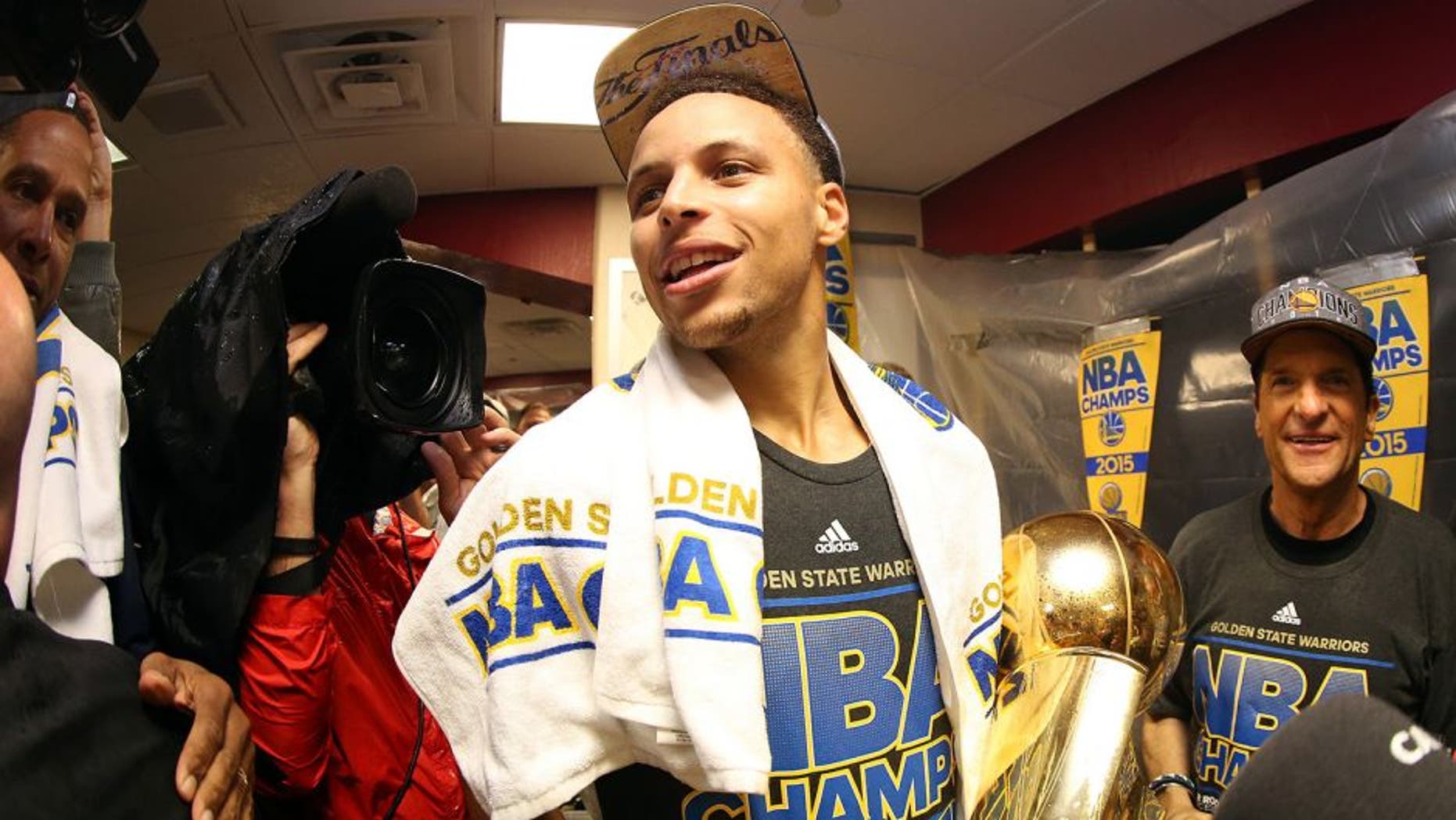 CLEVELAND, OH - JUNE 16: Stephen Curry #30 of the Golden State Warriors celebrates with the Larry O'Brien NBA Championship Trophy in the locker room after they defeated the Cleveland Cavaliers 105 to 97 in Game Six of the 2015 NBA Finals at Quicken Loans Arena on June 16, 2015 in Cleveland, Ohio. NOTE TO USER: User expressly acknowledges and agrees that, by downloading and or using this photograph, user is consenting to the terms and conditions of Getty Images License Agreement. (Photo by Ezra Shaw/Getty Images)