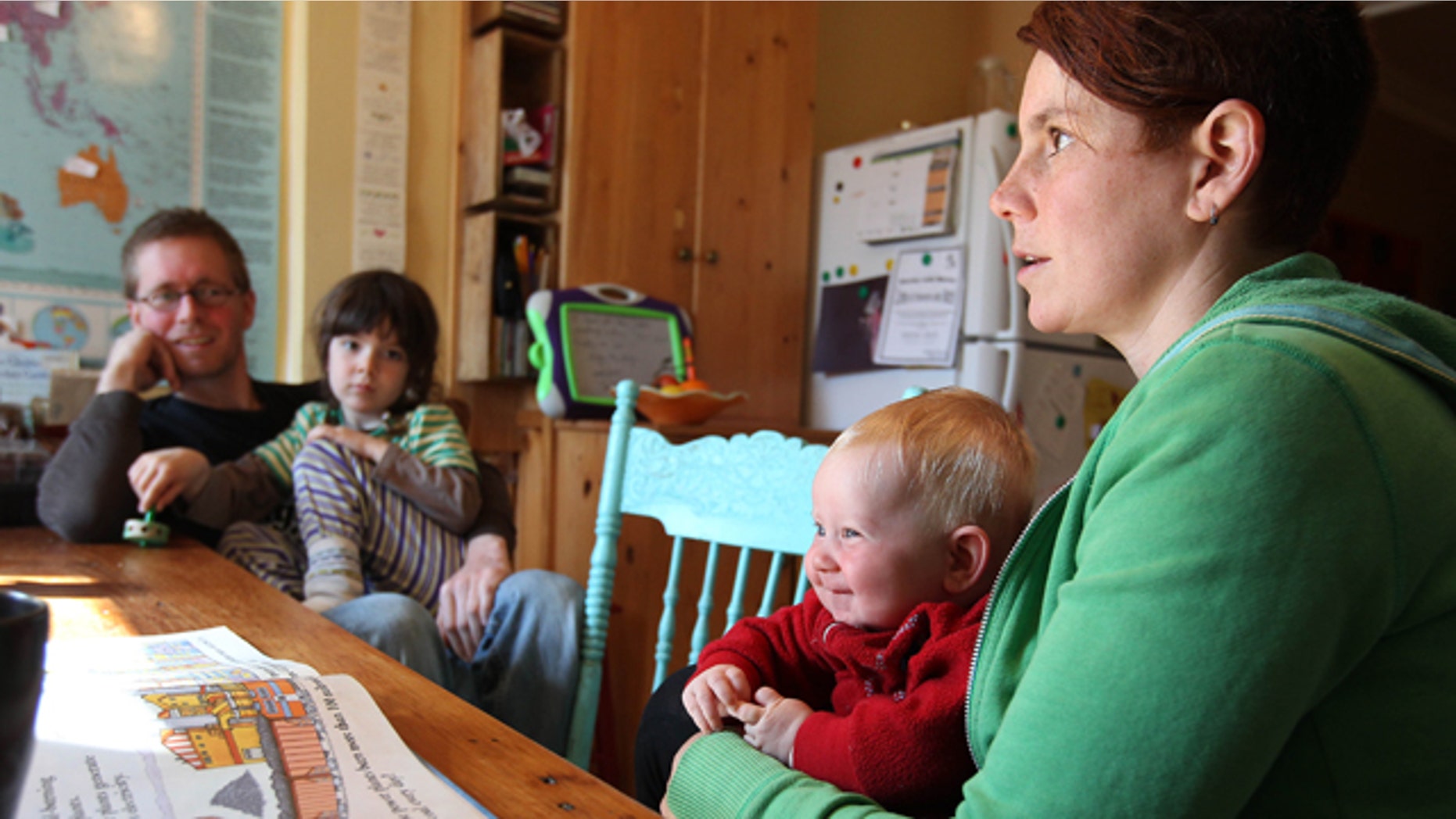 Storm, a four-month-old Toronto child being raised as genderless, smiles while being held by mother Kathy Witterick, 38, as father David Stocker, 39, and brother Jazz, 5, look on. (Steve Russell/Toronto Star/GetStock.com)