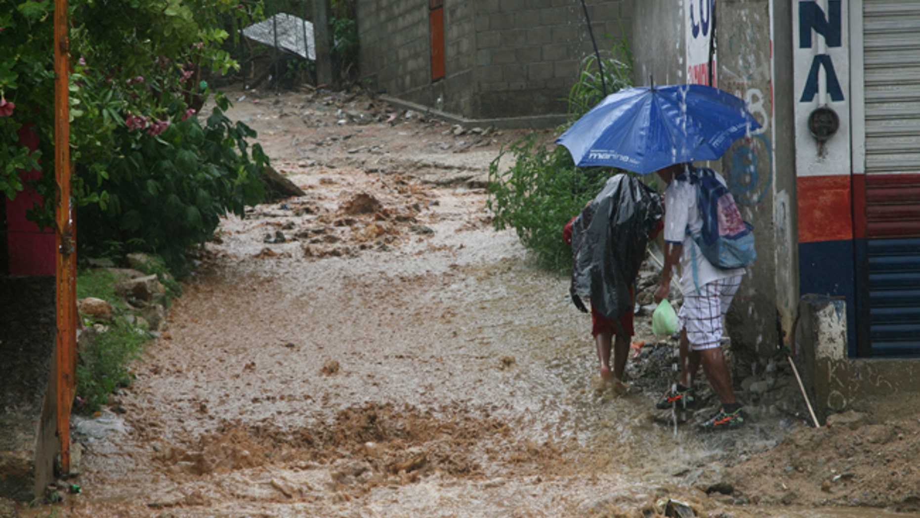 People walk under a downpour on a flooded street in Acapulco, Mexico, Thursday, Sept. 14, 2017.