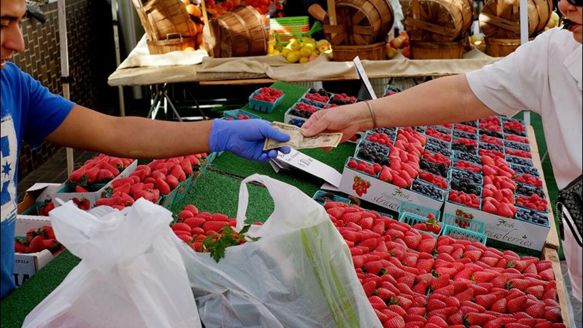 A shopper pays for fruit and assorted produce at a farmer's market in downtown Los Angeles.