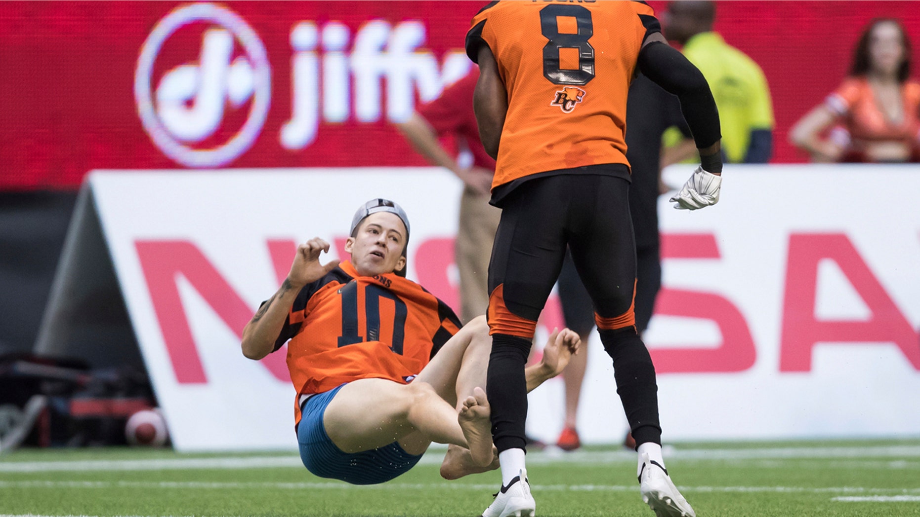 B.C. Lions' Marcell Young (8) knocks down a spectator that ran onto the field of play during the first half of a CFL football game against the Montreal Alouettes in Vancouver, British Columbia, Saturday June 16, 2018. (Darryl Dyck/The Canadian Press via AP)