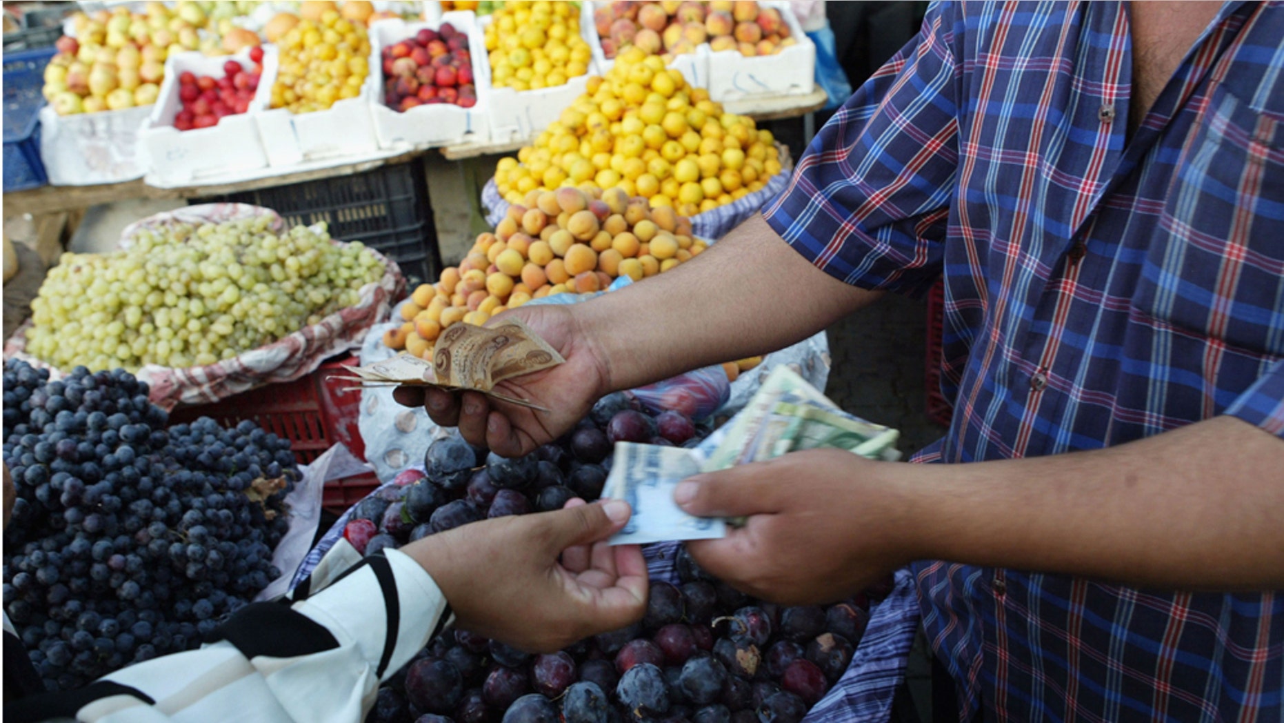 BAGHDAD, IRAQ - JULY 08: A fruit vendor makes a sale as people enjoy the evening on a street in the capital as life continues on despite the violence in the country July 8, 2004 in Baghdad, Iraq. Violence and frequent bombings have not deterred the Iraqi street culture, which remains busy and vibrant. (Photo by Joe Raedle/Getty Images)