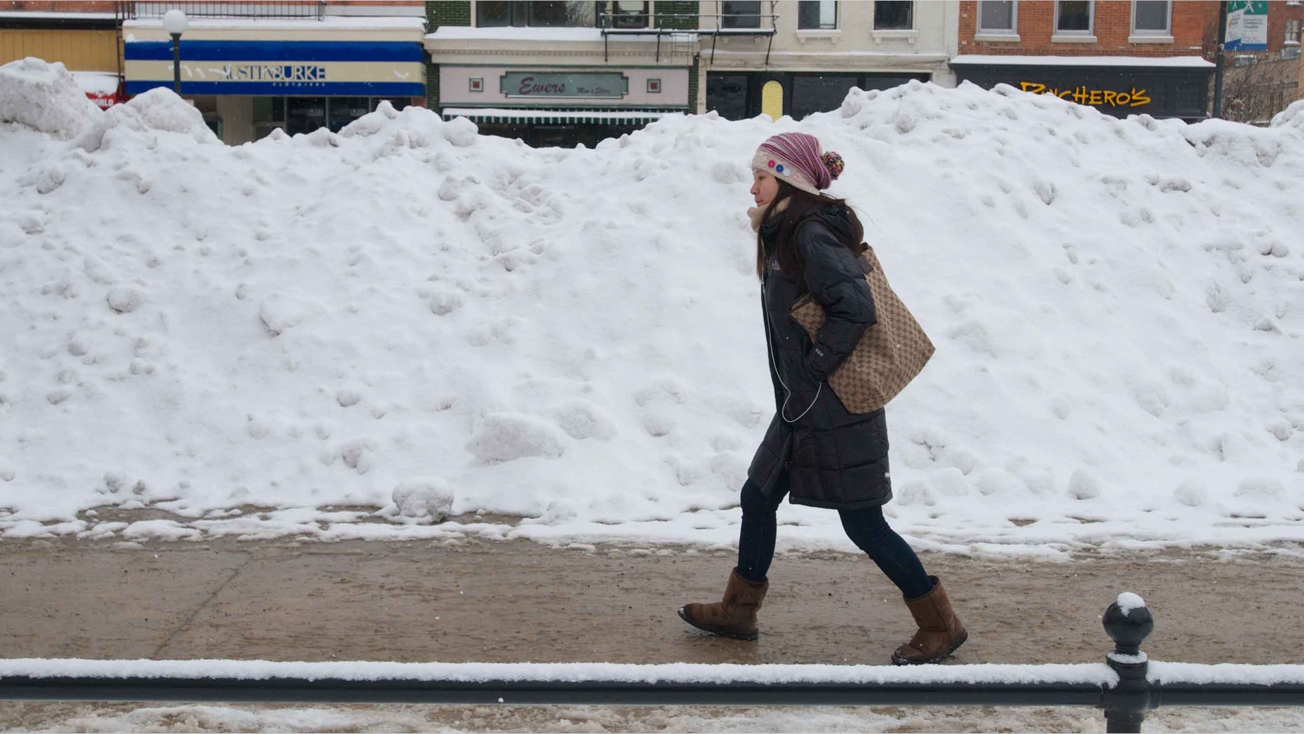 IOWA CITY, IOWA - FEBRUARY 22: A University of Iowa student walks past a snowbank after a winter storm left more than six inches of snow on February 22, 2013 in Iowa City, Iowa. The winter blizzard continues to move across the entire midwest, dumping up to a foot of snow in places as it moves east. (Photo by David Greedy/Getty Images)