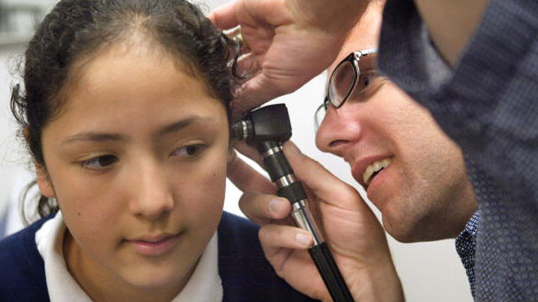 CICERO, IL - MAY 11: Dr. Michael Paul, with the Pediatric Mobile Health Unit of Loyola University Medical Center, performs a physical exam for incoming fifth-graders on fourth-grader Bennita Correa outside David Burnham Elementary School May 11, 2004 in Cicero, Illinois. The Pediatric Mobile Health Unit, the first if its kind in the world, is a 40-foot long truck which accommodates two patient examination rooms, a laboratory, a medical records area and hearing booth. Since 1998 more than 50,000 uninsured and underinsured children in the Chicago area have been evaluated and treated at the unit. (Photo by Tim Boyle/Getty Images)