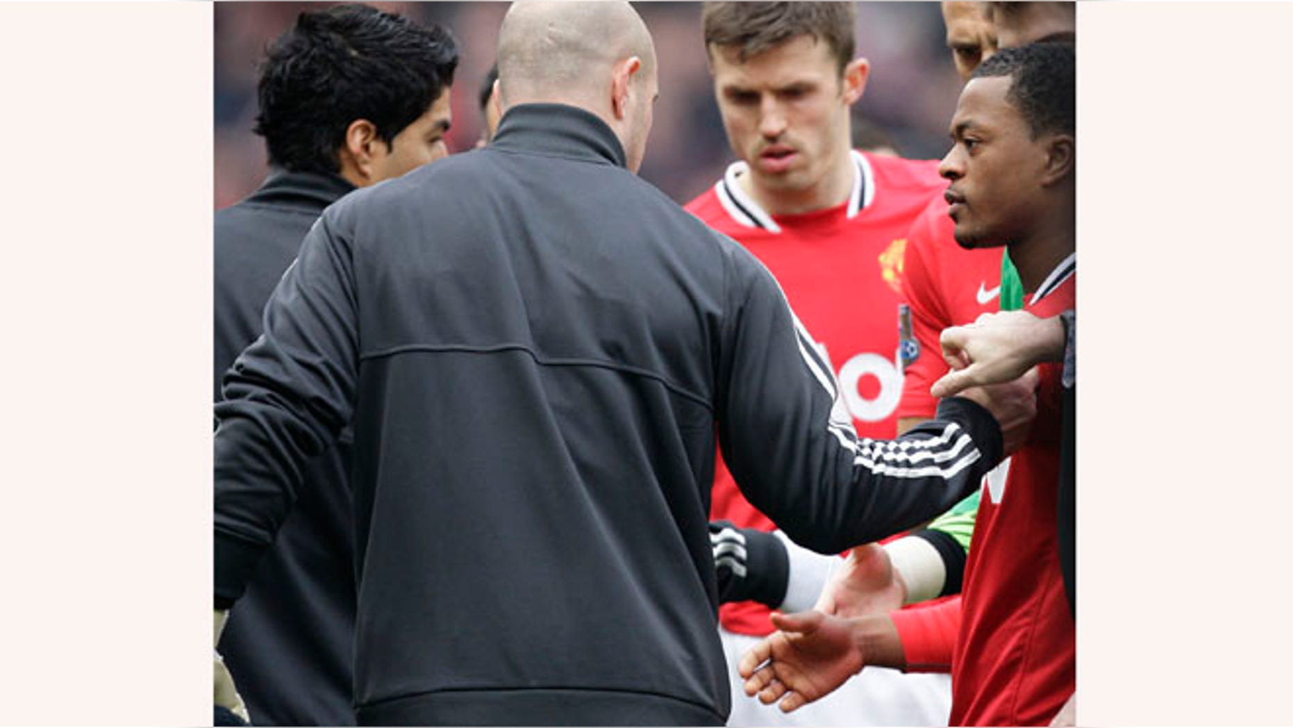 Manchester United's Patrice Evra, right, attempts to shake hands with Liverpool's Luis Suarez, left, during their English Premier League soccer match at Old Trafford Stadium, Manchester, England, Saturday, Feb. 11, 2012. Suarez refused to shake the hand of the Manchester United defender Evra, their first meeting since the Liverpool forward was banned for eight matches for racially abusing Evra in October 2011.(AP Photo/Jon Super)