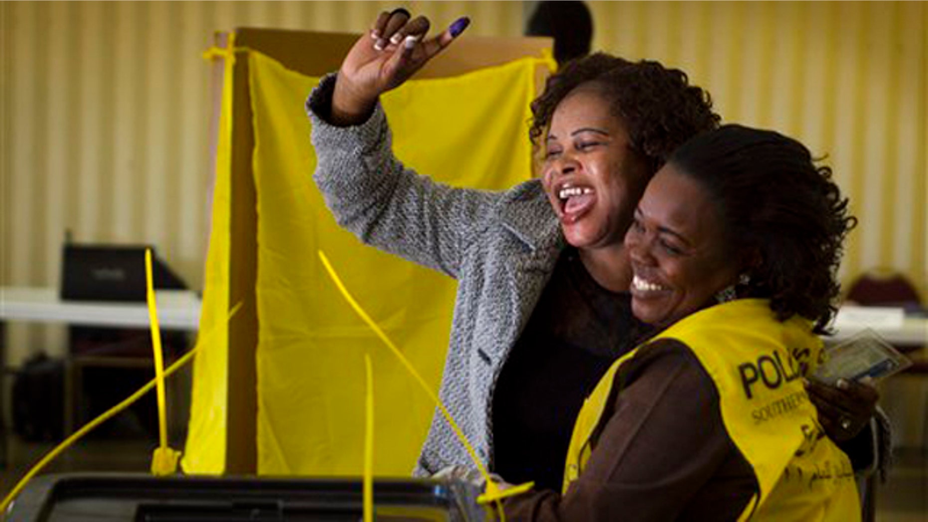Jan 9, 2011: Helen Dembite, center, who came all the way from Queensland, Australia, just to vote cheers with her ink stained finger in the air next to Polling Staffer, Gisma Dabura, right, during the referendum vote on whether South Sudan will become independent from Sudan at St. James Catholic Church in Glendale, Ariz. The polling place in Glendale was one of only eight in the entire country. The ink stained finger shows that an individual voted and ensures the individual cannot vote again.