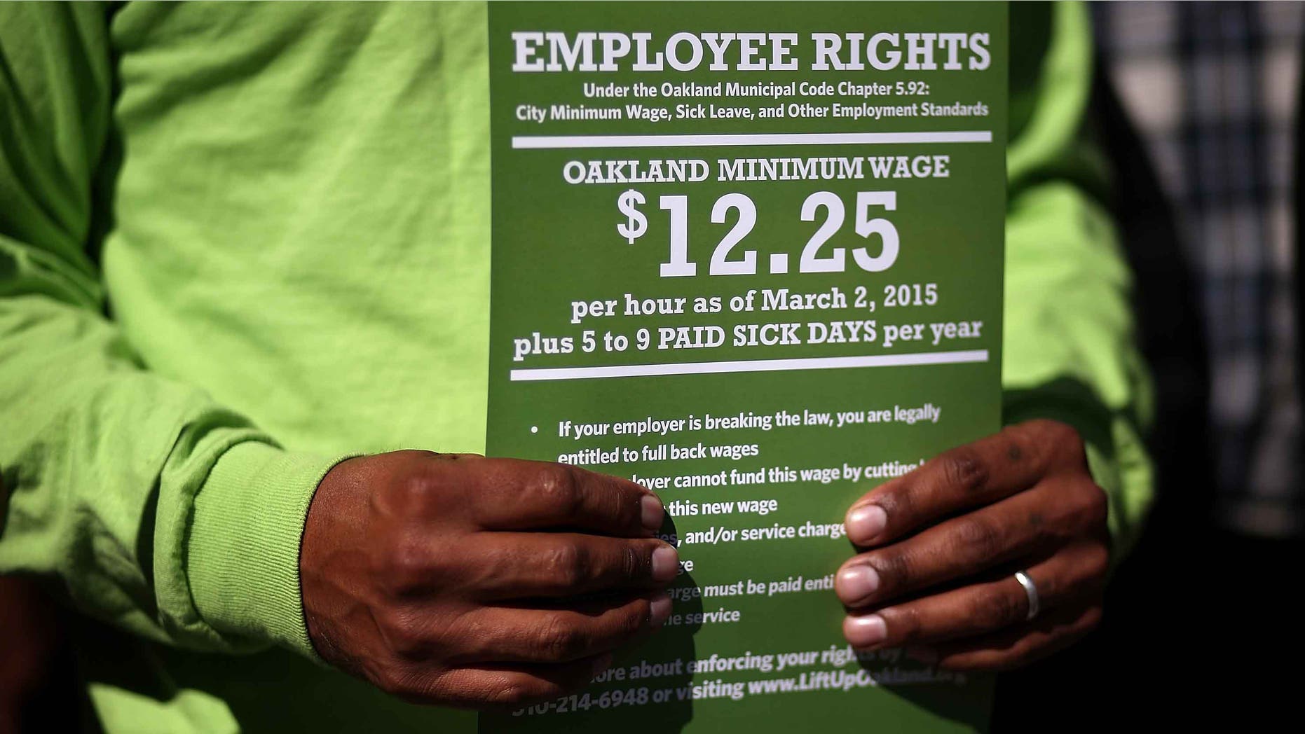 OAKLAND, CA - FEBRUARY 27: A supporter of Oakland's minimum wage increase holds a sign during a celebration rally outside of Oakland City Hall on February 27, 2015 in Oakland, California. Dozens of minimum wage workers gathered on the steps of Oakland City Hall to celebrate a $3 increase in the city's minimum wage to $12.25 an hour. Voters passed measure FF in November with 81 percent voting in favor of the wage increase. The new wage goes into effect on March 2. (Photo by Justin Sullivan/Getty Images)