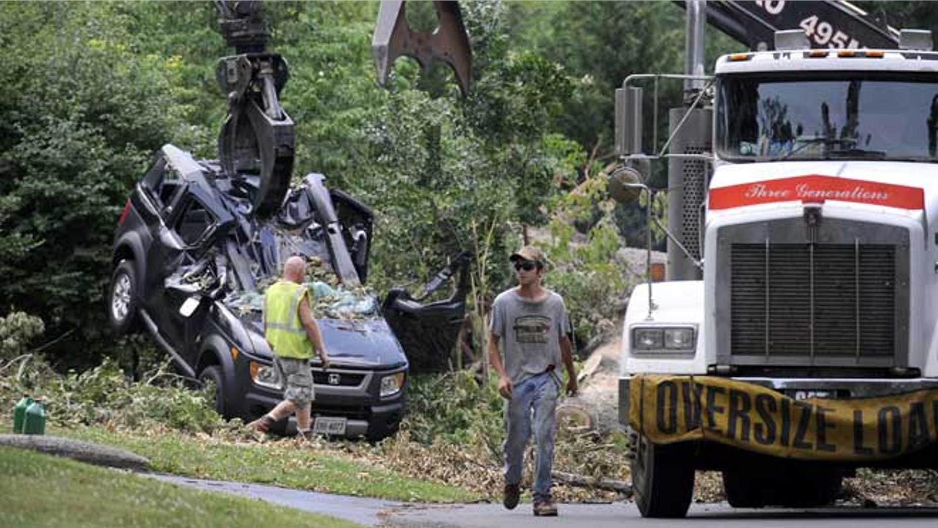 July 4, 2012: In the process of cutting up and removing an Oak tree blocking Inglewood Road, in Lynchburg, Va., a crane lifts the crushed Honda Element that Amy Scott and her son, Cooper, were inside of Friday night as the tree fell on top of them.