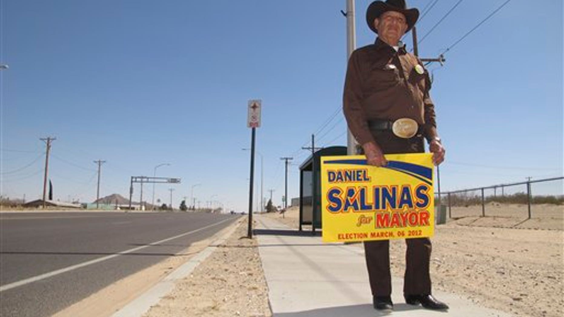 Everardo Holguin, 75, stands with a poster supporting his candidate for mayor Tuesday March. 6, 2012, in Sunland Park, New Mexico. The city of 14,000 inhabitants has undergone a turbulent mayoral campaign with candidate Gerardo Hernandez involved in a sex scandal and Mayor-elect Daniel Salinas facing charges of extorting his rival and a city official. (AP Photo/Juan Carlos Llorca)
