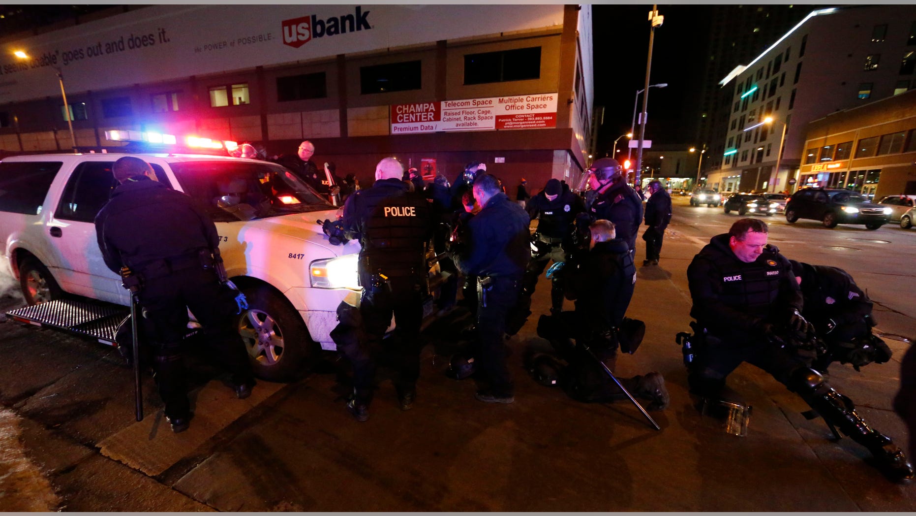 Denver police officers don gas masks and riot gear as they prepare to move back Broncos fans celebrating Denver's win in the Super Bowl.