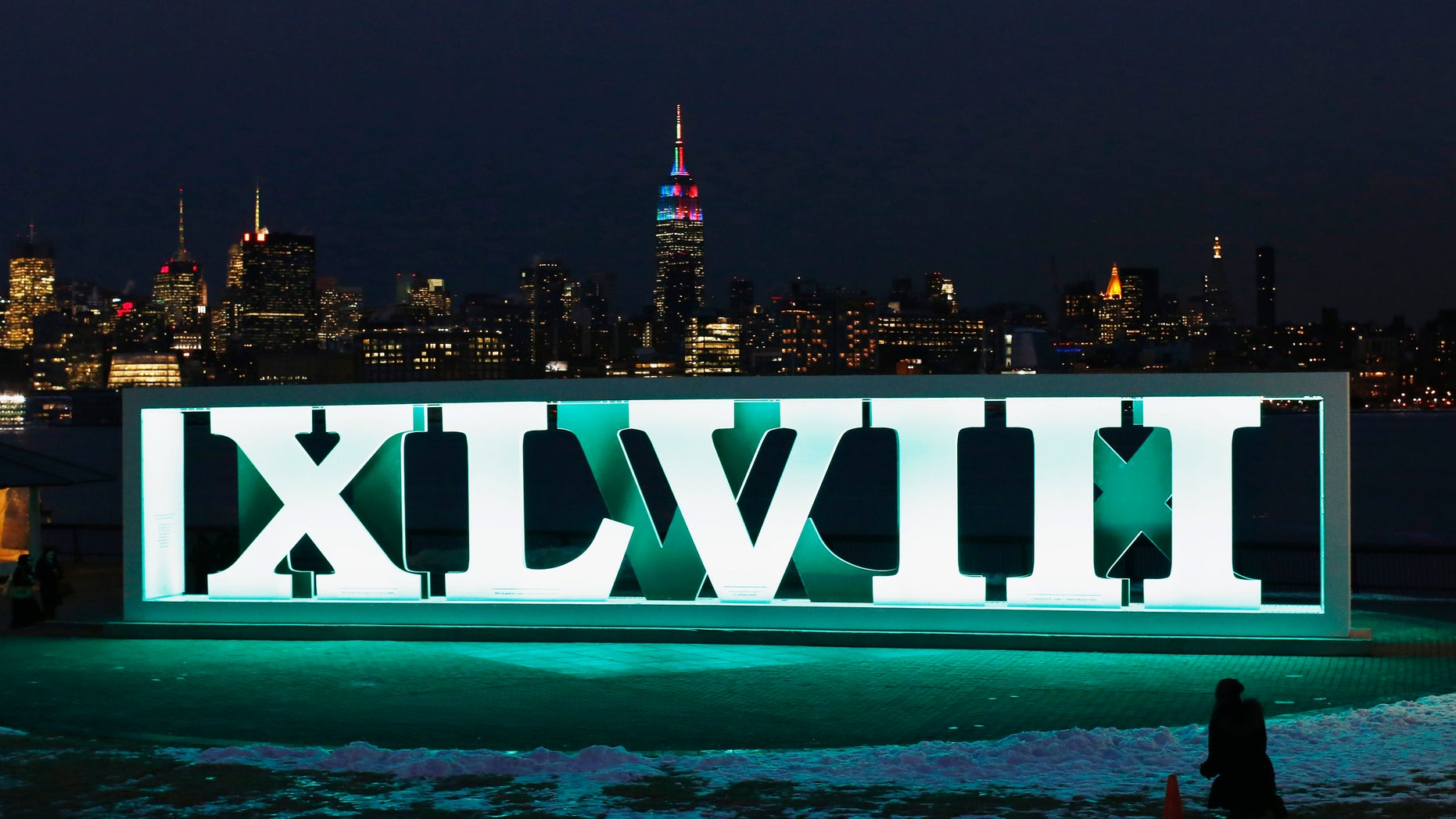 The New York skyline and the Empire State Building are seen in the distance as a woman tries to take a picture of Roman numerals for NFL Super Bowl XLVIII football game in Hoboken, New Jersey.