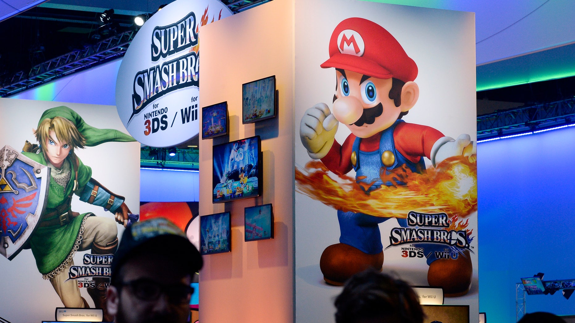Attendees walk past Nintendo Co.'s Super Smash Bros. signage at the 2014 Electronic Entertainment Expo, known as E3, in Los Angeles, California June 11, 2014.
