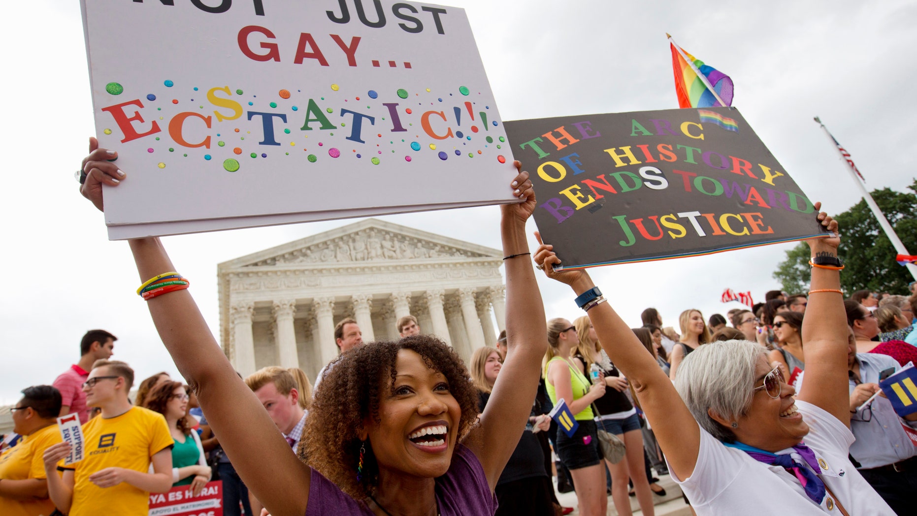Ikeita Cantu, left, and her wife Carmen Guzman, of McLean, Va., hold up signs as they celebrate outside of the Supreme Court in Washington, Friday June 26, 2015, after the court declared that same-sex couples have a right to marry anywhere in the US. The couple was married in Canada in 2009 when gay marriage was illegal in Virginia. (AP Photo/Jacquelyn Martin)