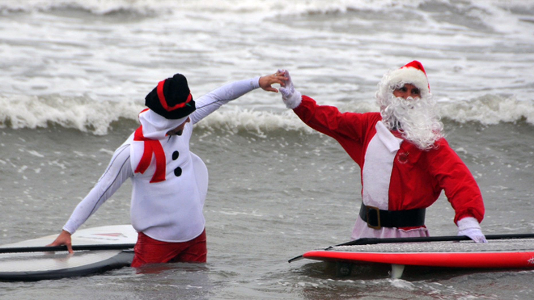 Dec. 24, 2013: George Trosset Jr., dressed as a snowman, left, and his dad, event organizer George Trosset, high-five each other out in the waves during the fourth annual "surfing Santas" event in Cocoa Beach, Fla.