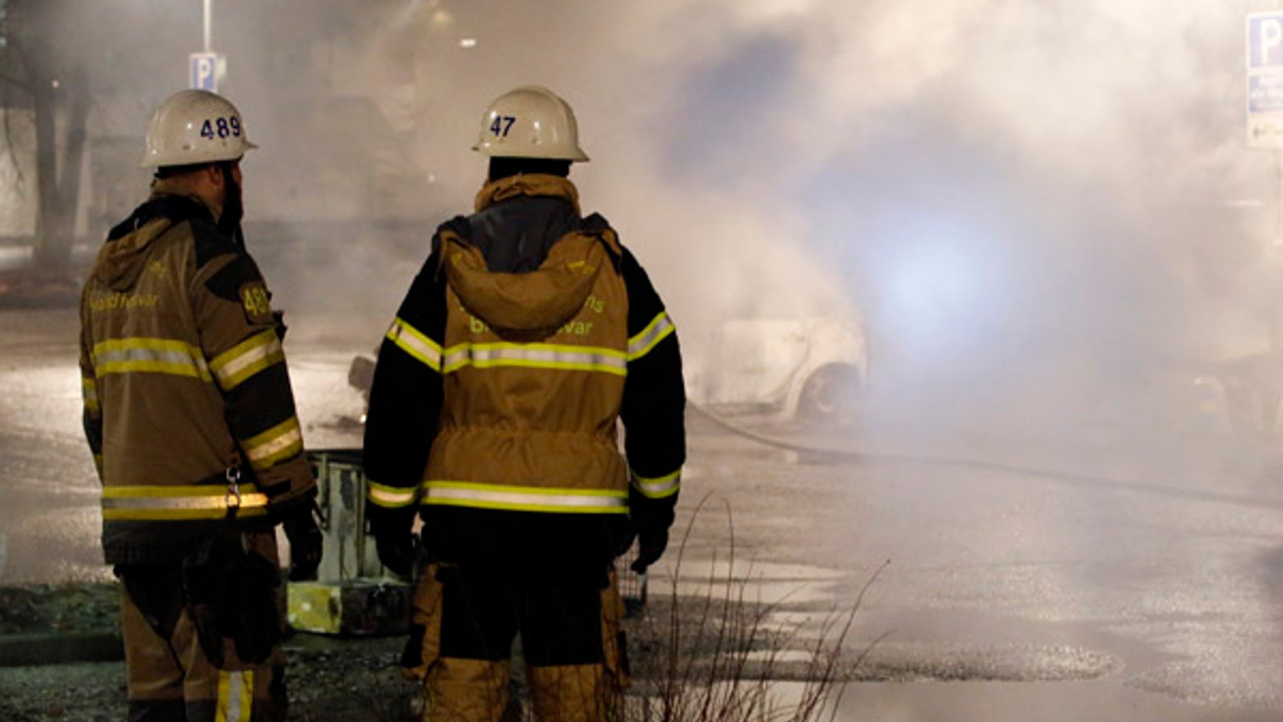 Firefighters survey the scene in the suburb of Rinkeby where riots erupted on Monday night.