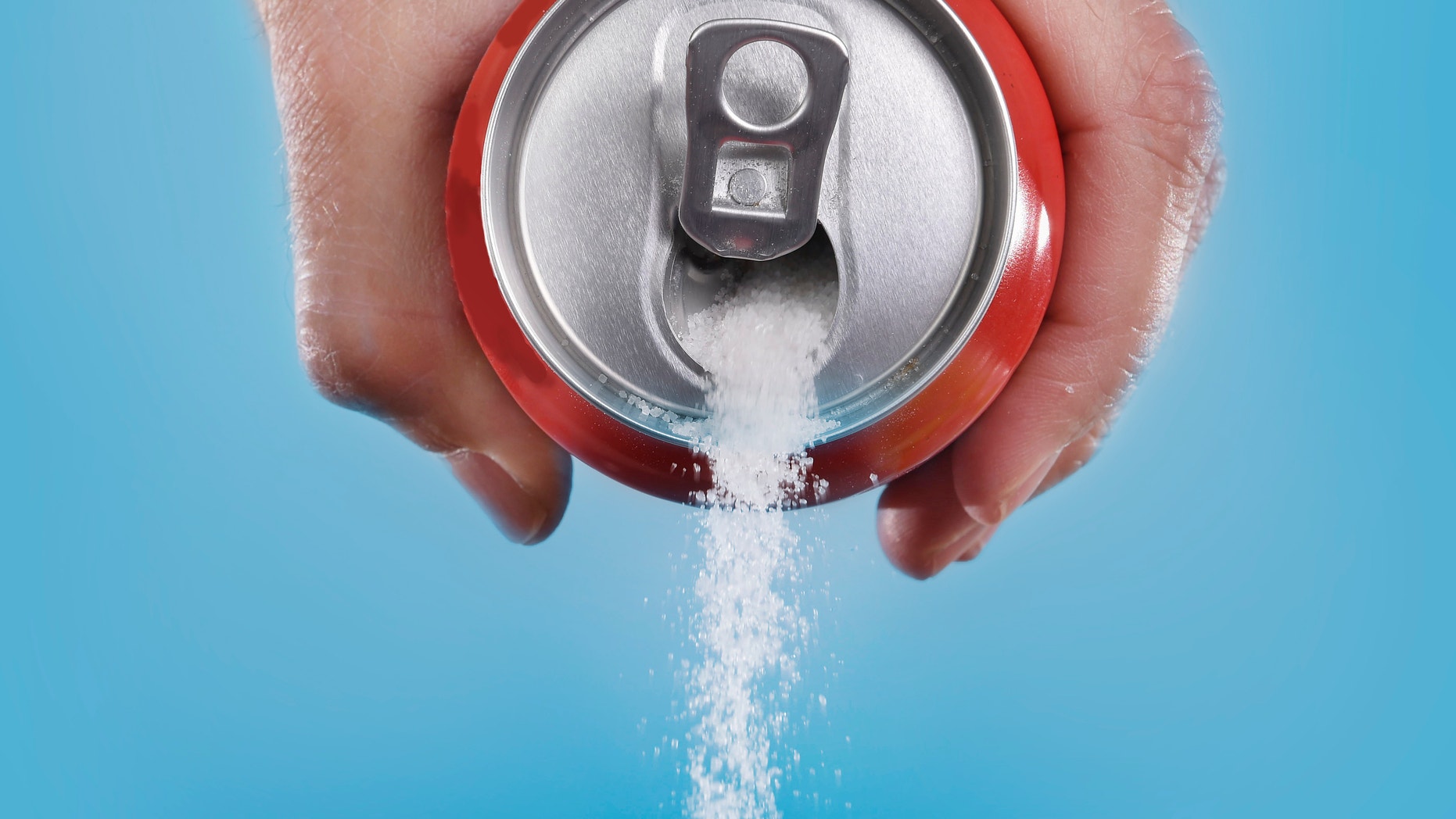 hand holding soda can pouring a crazy amount of sugar in metaphor of sugar content of a refresh drink isolated on blue background in healthy nutrition, diet and sweet addiction concept