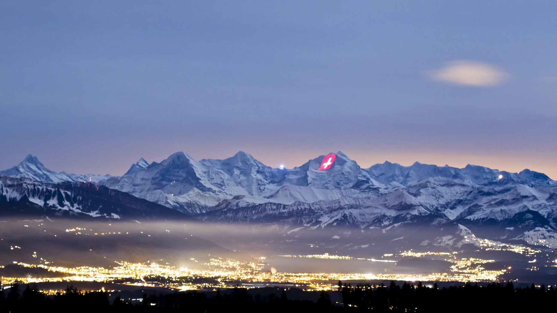 A giant light installation of the flag of Switzerland, by Swiss artist Gerry Hofstetter, illuminates the north face of the Jungfrau mountain. (REUTERS/Michael Buholzer)