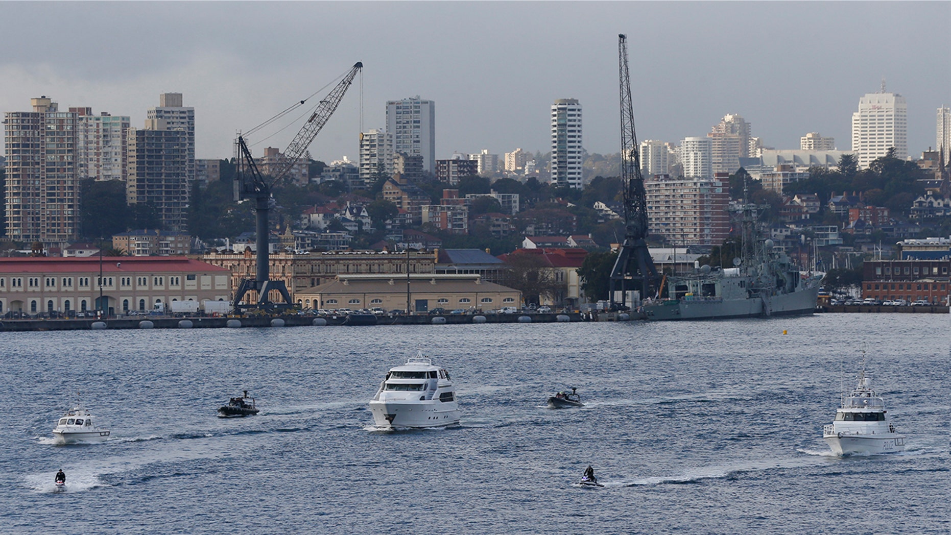 A flotilla including a motor launch crosses Sydney Harbor.