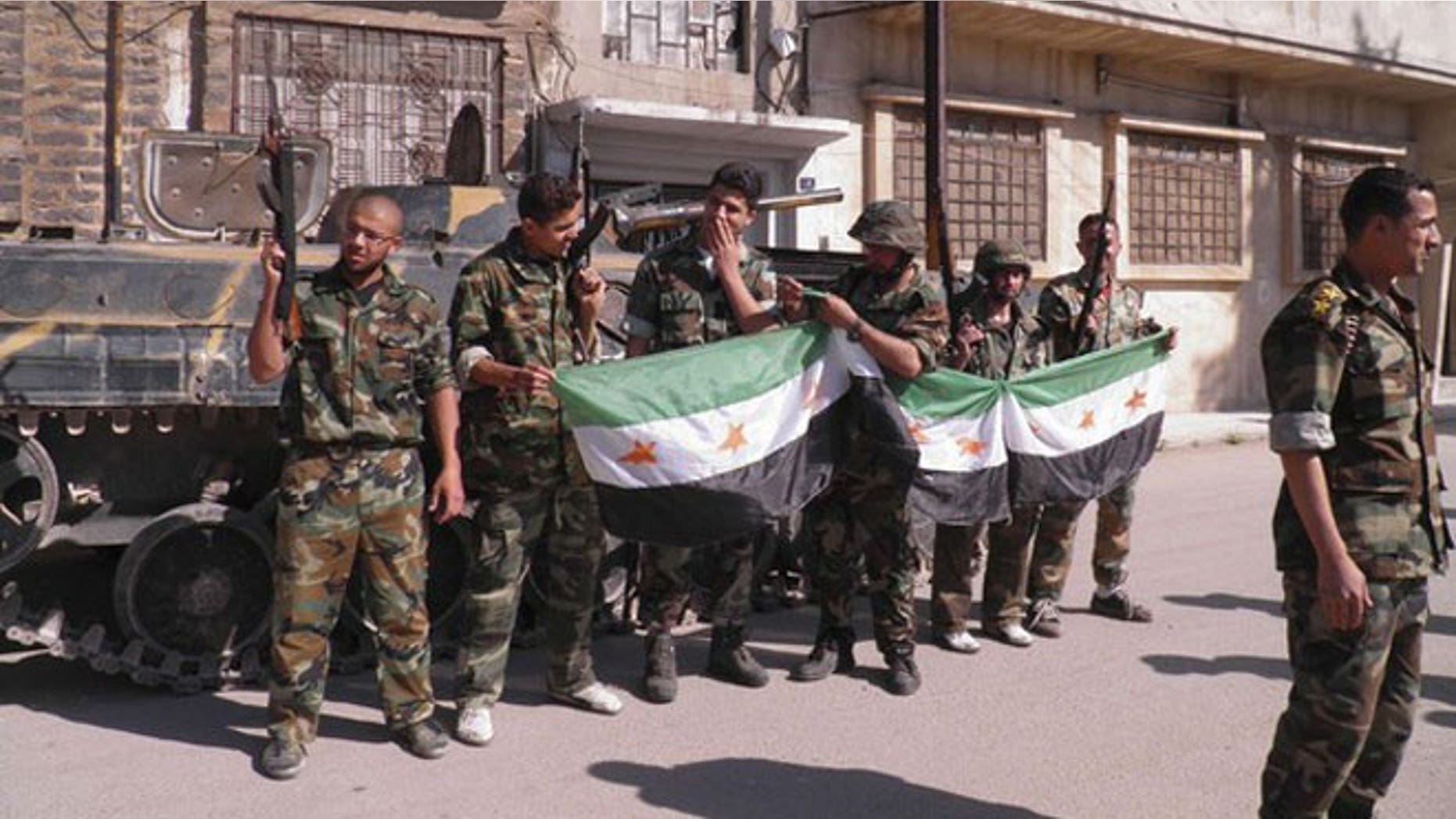 May 12, 2012: Syrian soldiers who defected to join the Free Syrian Army are seen in front of their armoured military vehicle at Khalidieh in Homs.