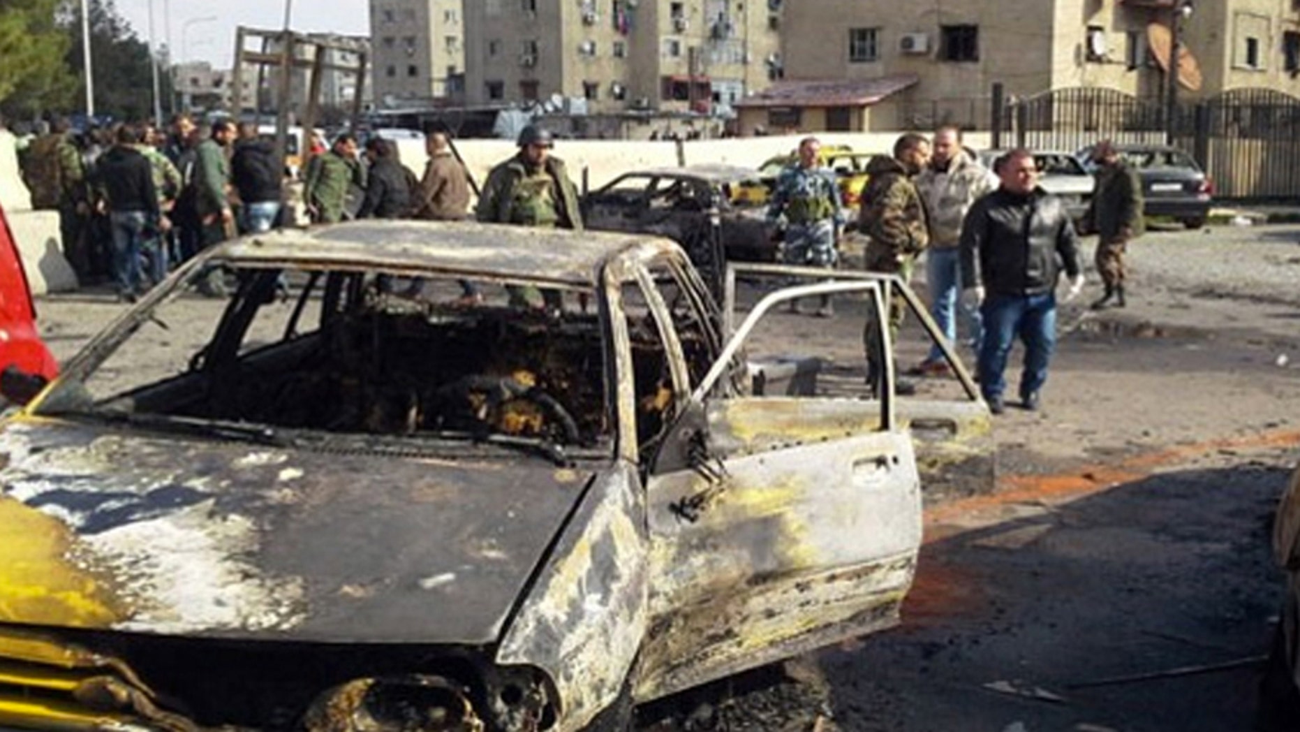 Feb. 9, 2016: In this photo released by the Syrian official news agency SANA, soldiers and plainclothes policemen gather at the scene of an explosion that killed tens of people and wounded others in the Syrian capital of Damascus.