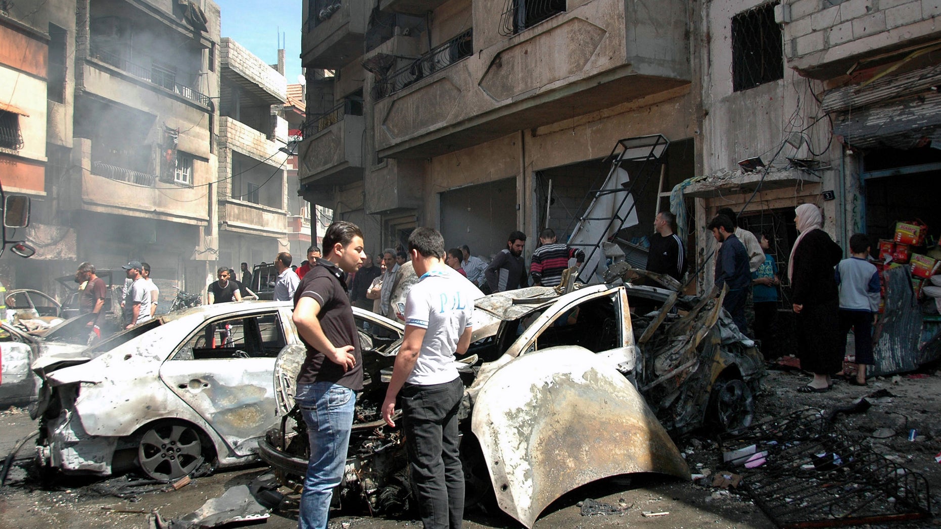 April 29, 2014 - Syrian people gather at the site of one of 2 car bombs that exploded in the pro-government district of Zahra in the central Syrian city of Homs, Syria. Photo provided by Syrian official news agency SANA.
