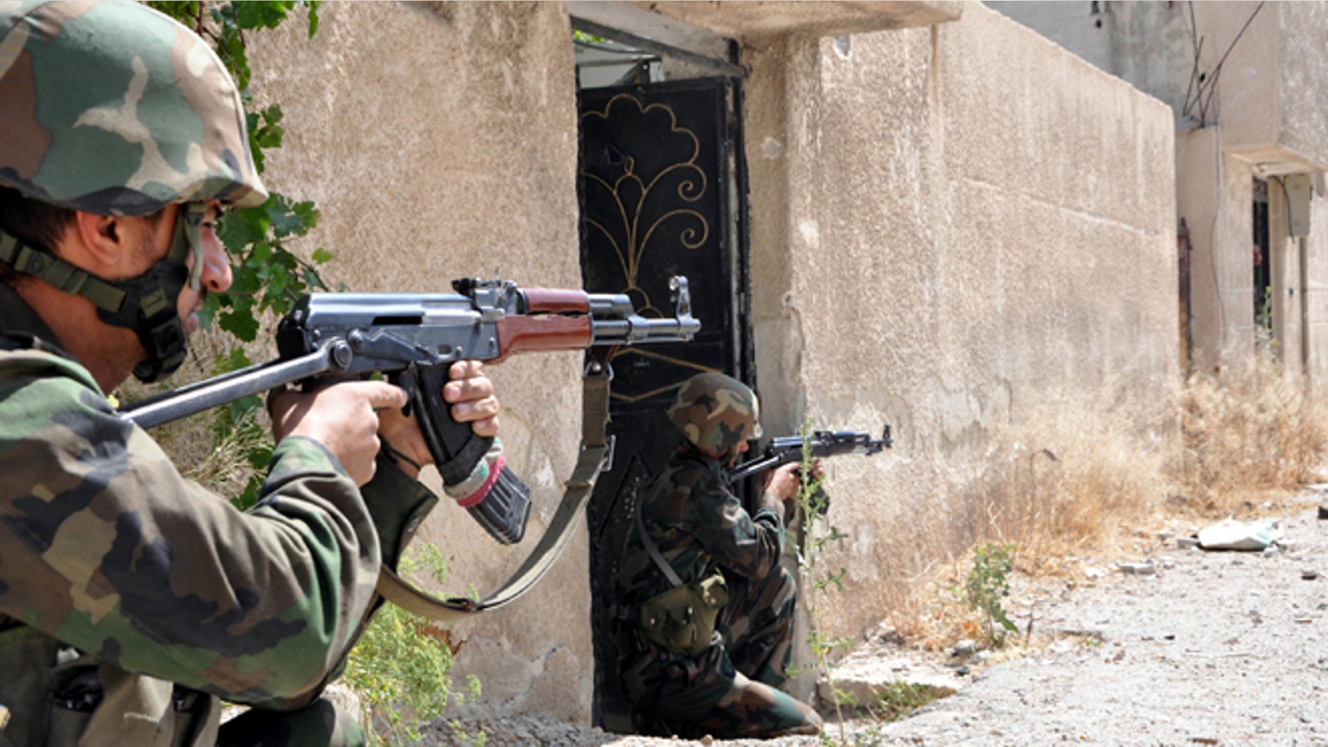 In this photo released on June 5, 2013 by the Syrian official news agency SANA, Syrian soldiers loyal to President Bashar Assad aim their weapons in an area near the Homs-Damascus highway, central Syria. Syrian troops and their Lebanese Hezbollah allies captured a strategic border town Wednesday after a grueling three-week battle, dealing a severe blow to rebels and opening the door for President Bashar Assad's regime to seize back the country's central heartland.
