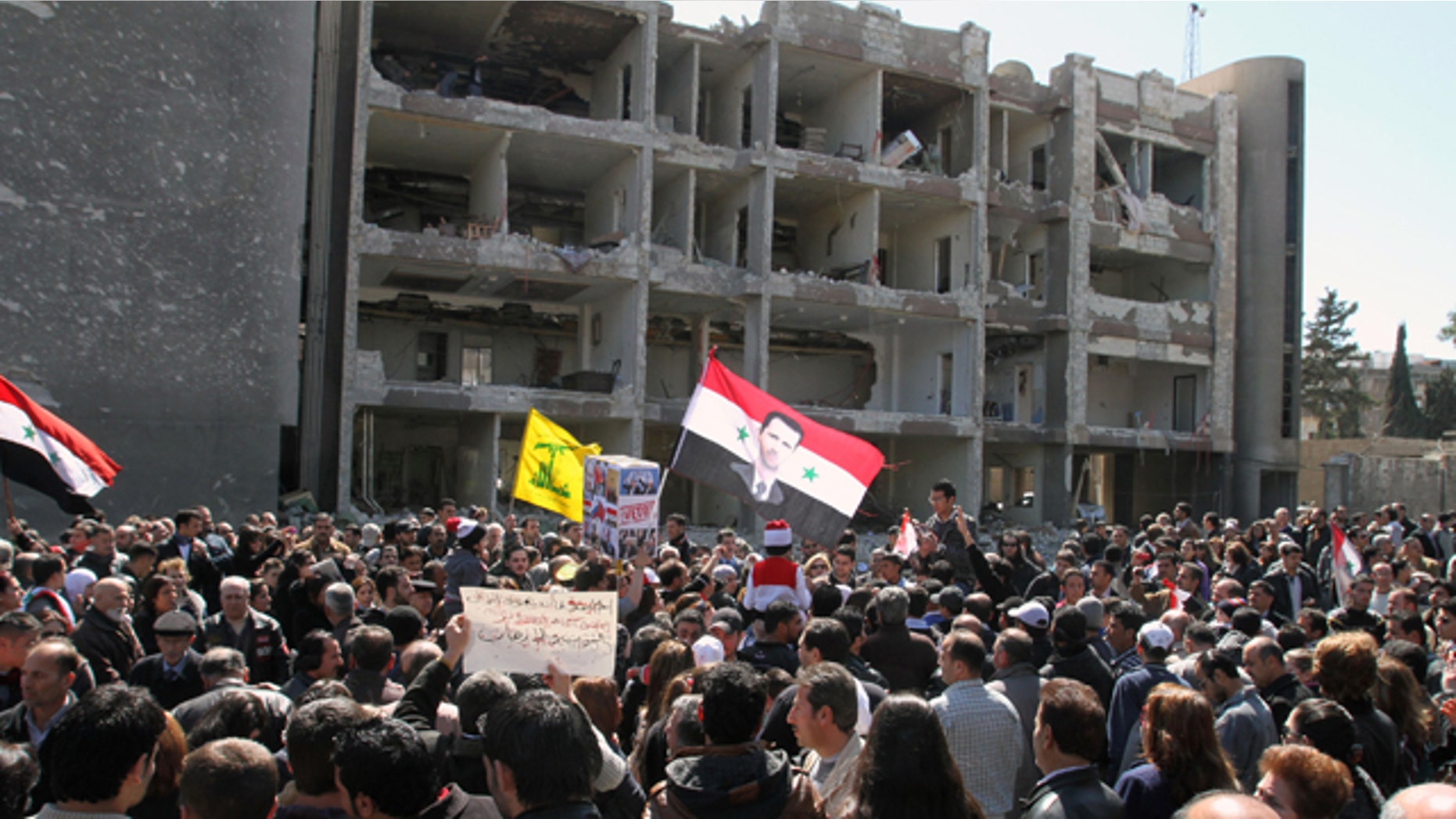 March 18, 2012: Thousands of people wave Syrian flags, one depicting President Bashar Assad, observe a silent march in front of a damaged government building on al-Qassa street in Damascus, Syria in memory of people who were killed a day earlier by two attacks in the capital Damascus. Three suicide bombings in the capital Damascus on Saturday killed several people. The government blamed those on the opposition, which it claims is made up of "terrorist" groups carrying out a foreign conspiracy.