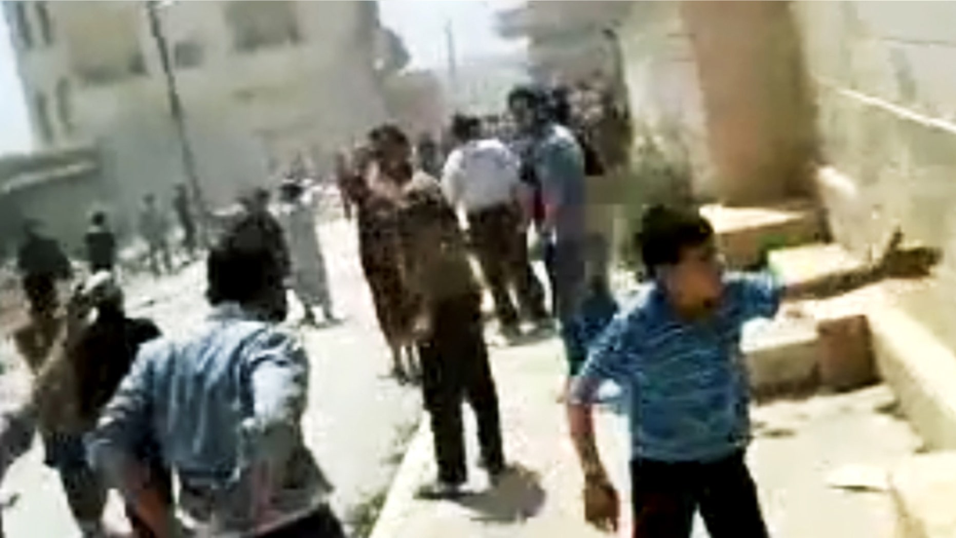 In this image made from amateur video released by the Shaam News Network and accessed Tuesday, May 15, 2012, purports to show Syrians running from gun shots in Khan Sheikhoun, Idlib, Syria.