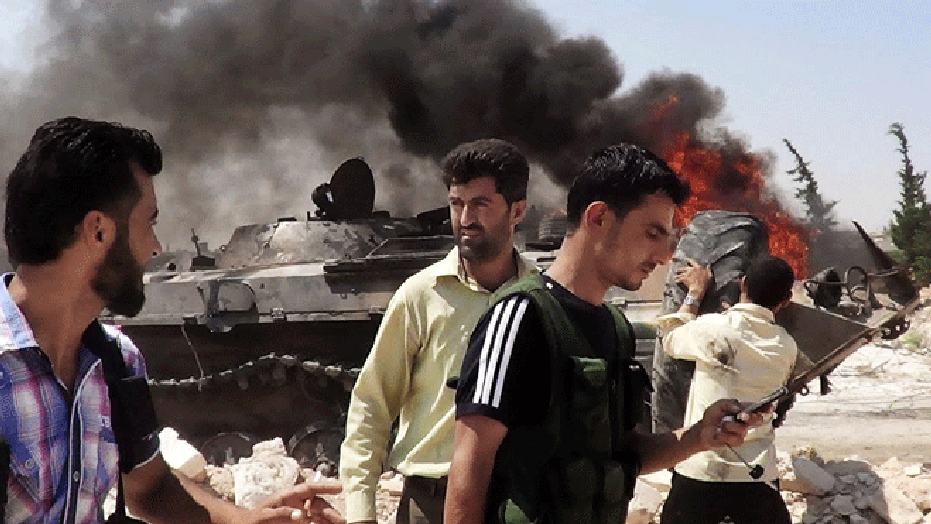 This citizen journalism image provided by Shaam News Network SNN, taken on Tuesday, July 3, 2012, purports to show Free Syrian Army soldiers standing near a Syrian military tank in Idlib, north Syria.