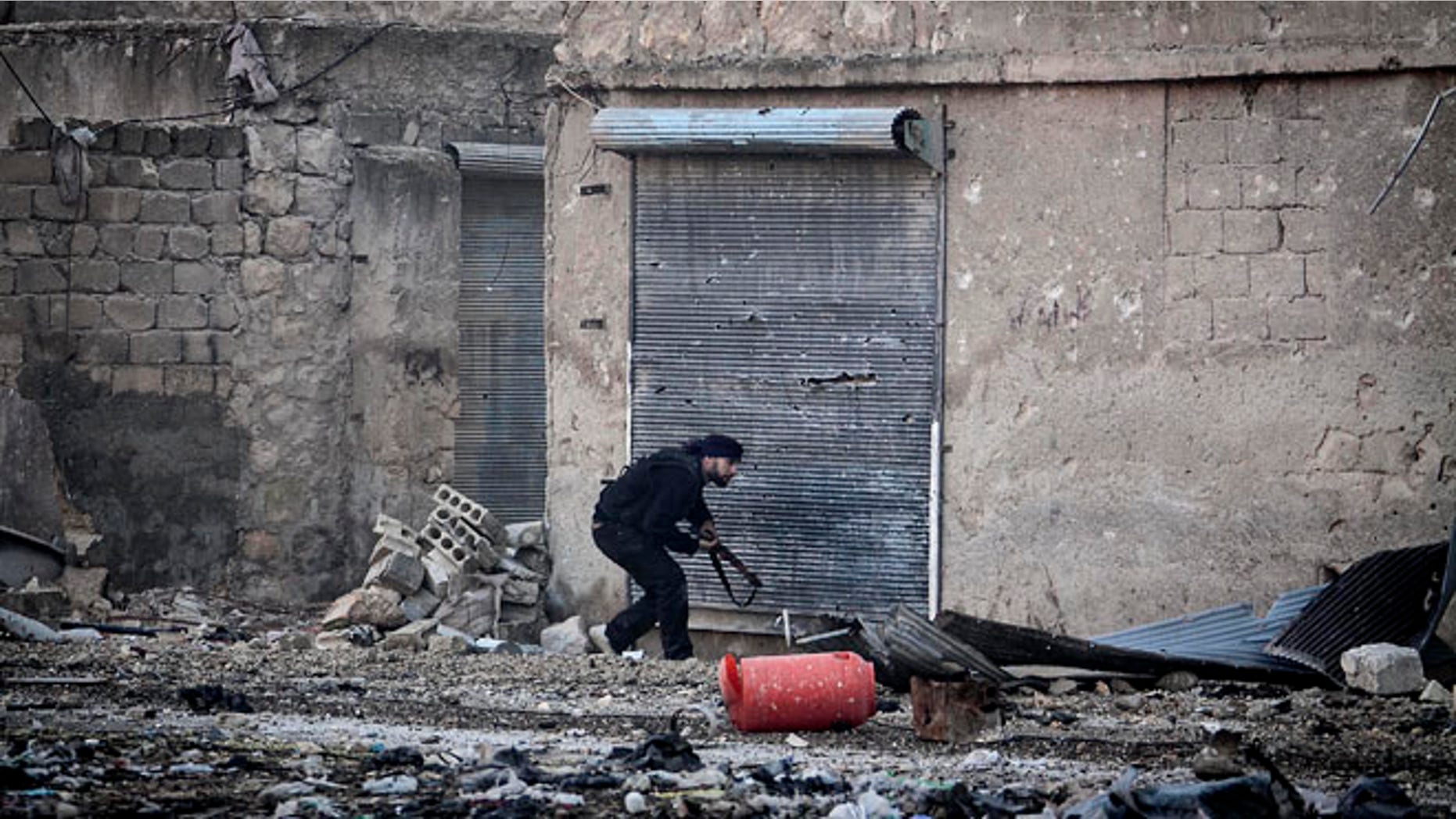 Dec. 5, 2012: A Free Syrian Army fighter runs for cover during heavy clashes with government forces, not pictured, in Aleppo, Syria.