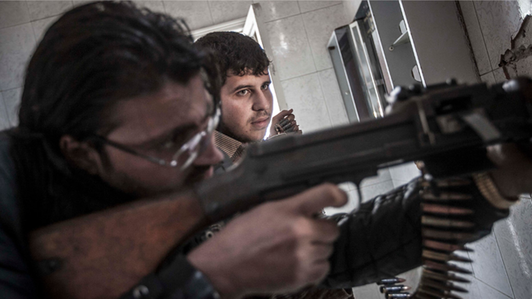 Oct. 28, 2012: In this photo, rebel fighters belonging to the Liwa Al-Tawhid group keep an eye over their enemy's position as they prepare to open fire as mortar explosions and gunshots are heard in the nearby battlefield in the Karm al-Jabel neighborhood of Aleppo, Syria.