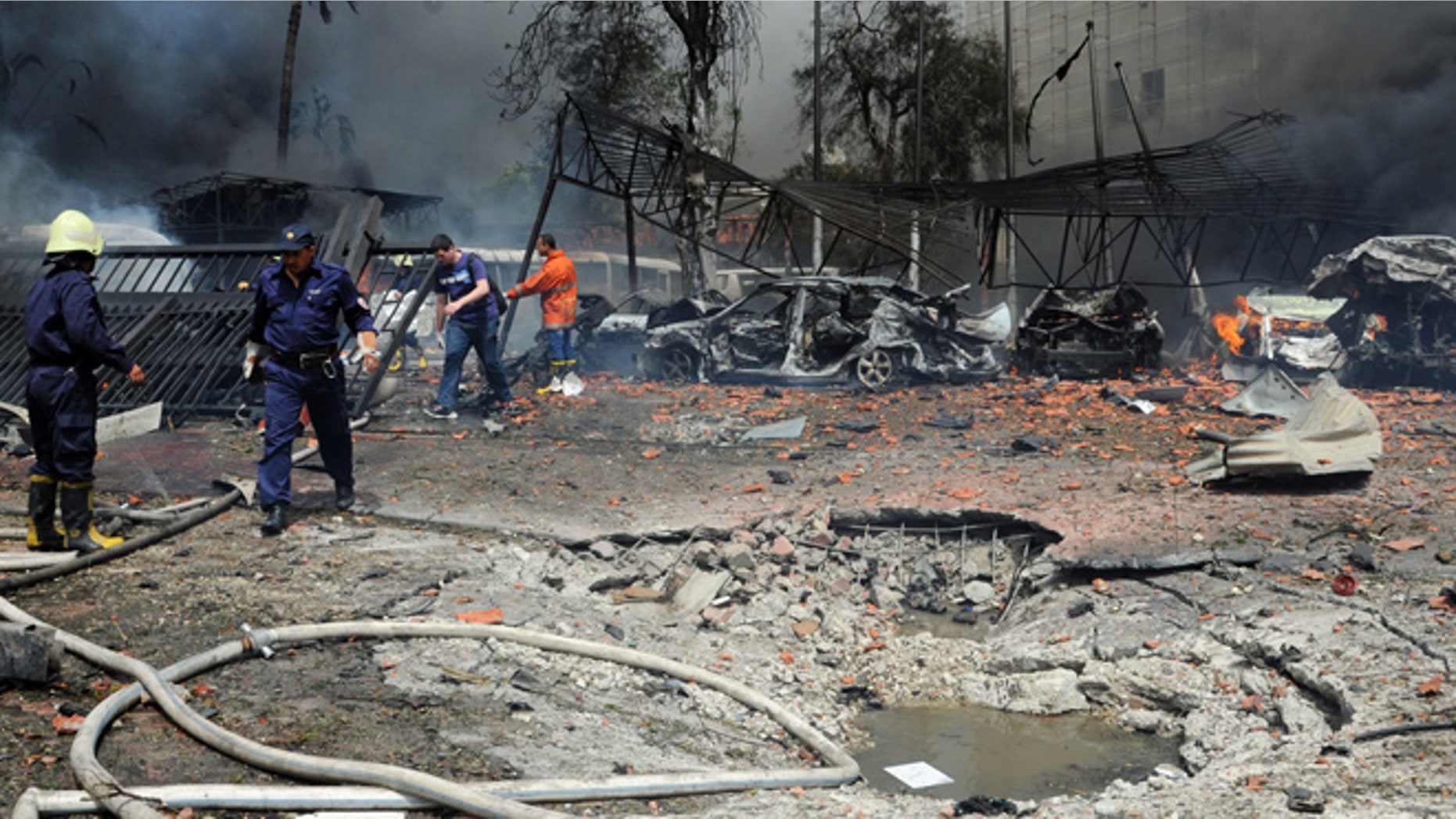 April. 8, 2013: This photo provided by the Syrian official news agency SANA, shows Syrian fire fighters extinguishing burning cars after a huge explosion shook the Sabaa Bahrat Square, one of the capital's biggest roundabouts, in Damascus, Syria. The car bomb rocked a busy residential and commercial district in central Damascus, killing at least a dozen people with tens more injured and causing heavy material damage, a Syrian government official said.