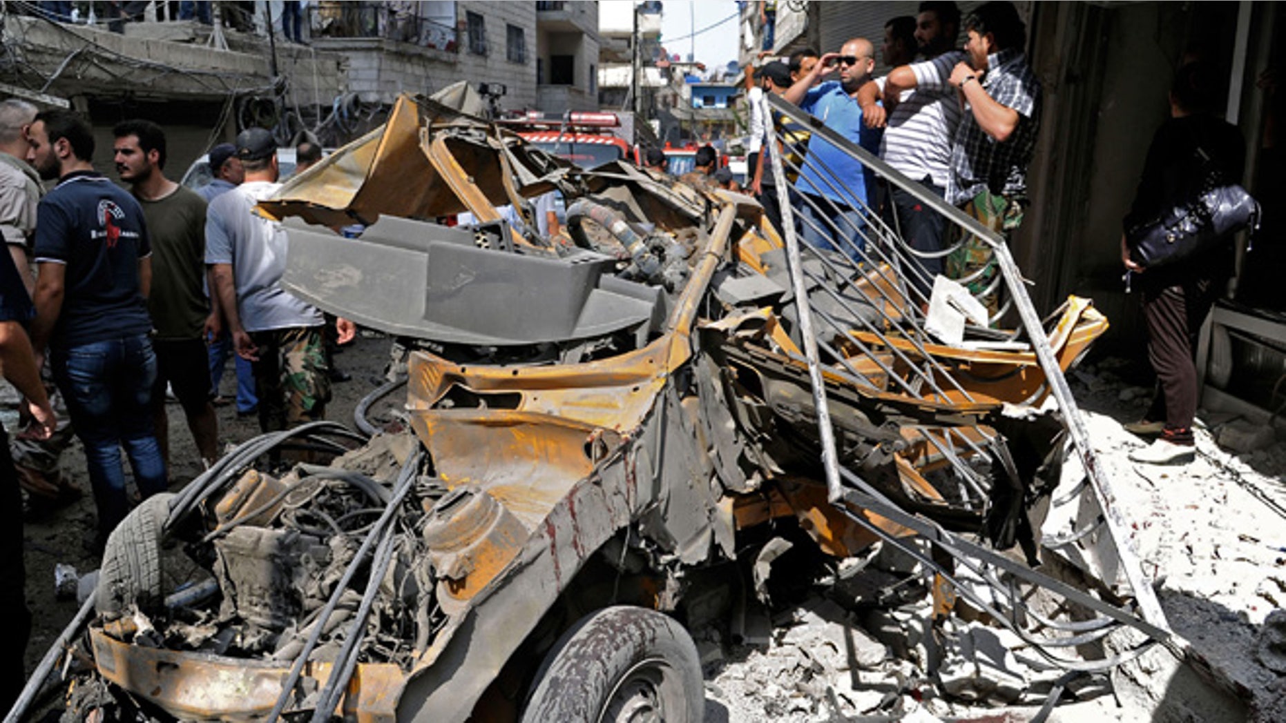 June 23, 2013: In this photo released by the Syrian official news agency SANA, Syrians investigate damages after two suicide bombings hit security compounds in Damascus, Syria.