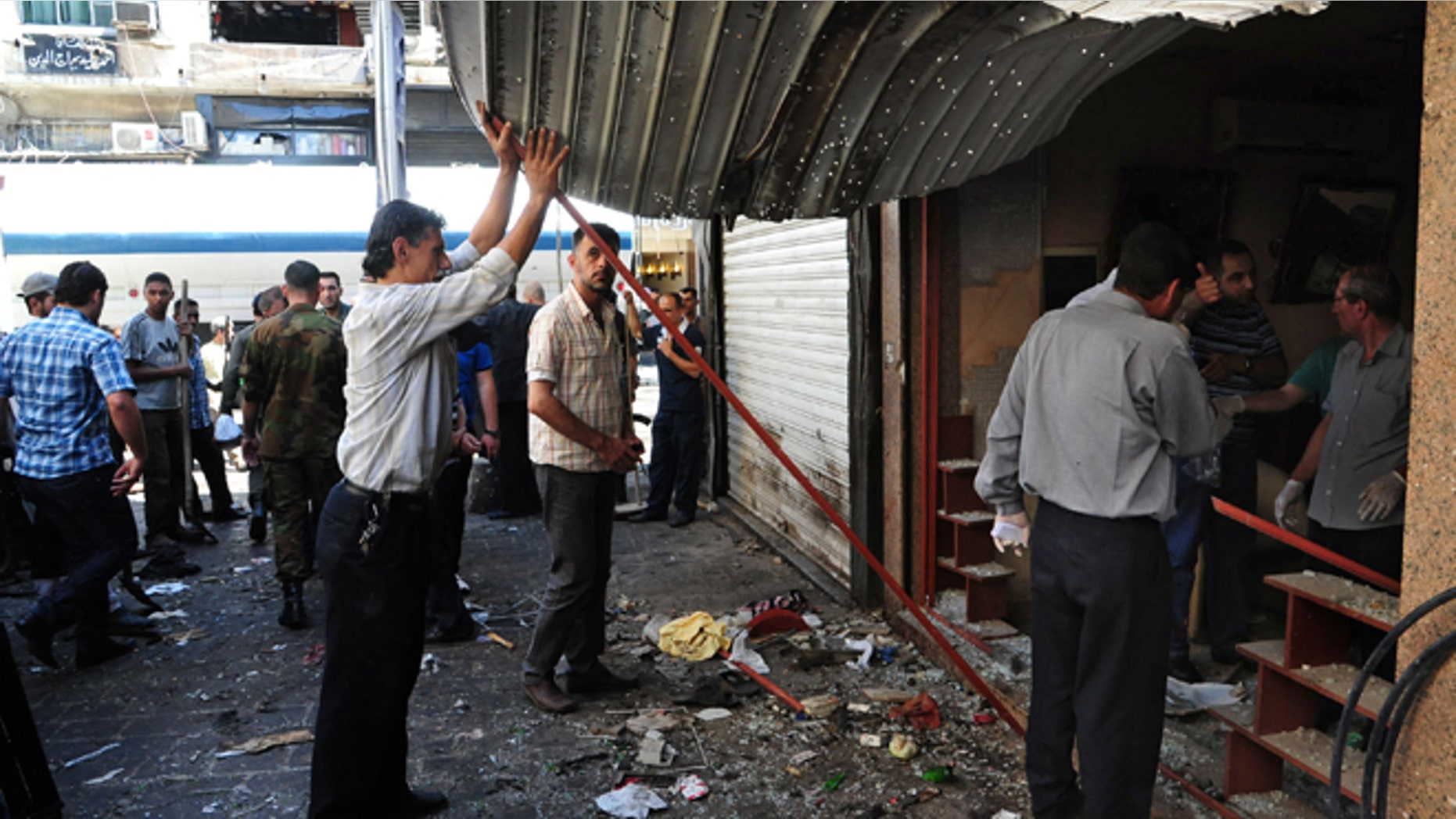 June 11, 2013: In this photo released by the Syrian official news agency SANA, Syrians inspect a damaged shop at a scene of two explosions in the central district of Marjeh, Damascus, Syria. Two explosions hit a central Damascus square Tuesday, killing and wounding dozens of people, activists and the state media reported. State TV said the blasts were caused by suicide bombers, while activists said they were bombs planted there in advance.