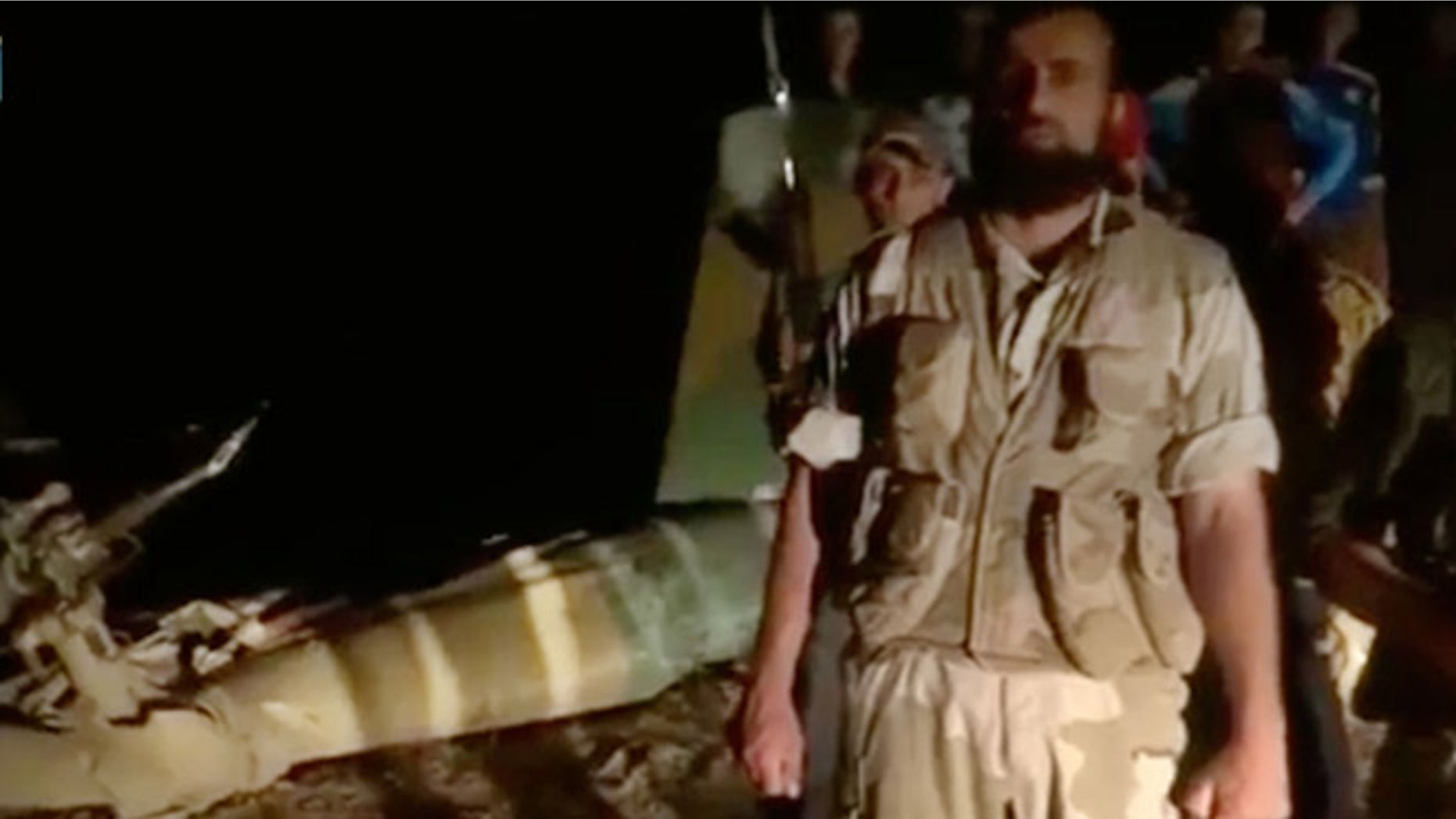 May 5, 2013: In this image taken from video obtained from the Shaam News Network, which has been authenticated based on its contents and other AP reporting, armed men stand near the wreckage of a military helicopter, left, in Deir el-Zour, Syria. Syrian rebels shot down a military helicopter in the country's east, killing eight government troops on board a day after opposition forces entered a sprawling military air base in the north, activists said Monday.