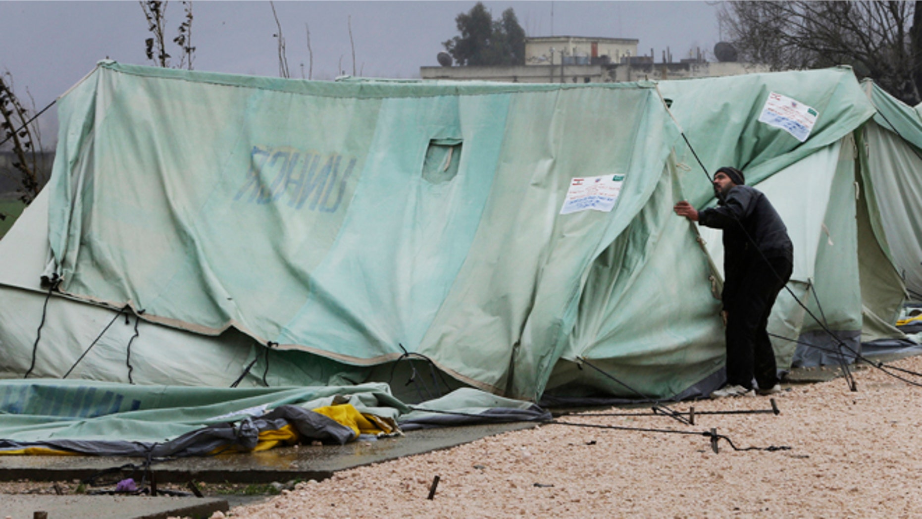 Jan. 7, 2013: A Syrian refugee man, fixes a tent that was blown off by the wind, at a temporary refugee camp in the eastern Lebanese town of Marj near the border with Syria, Lebanon.