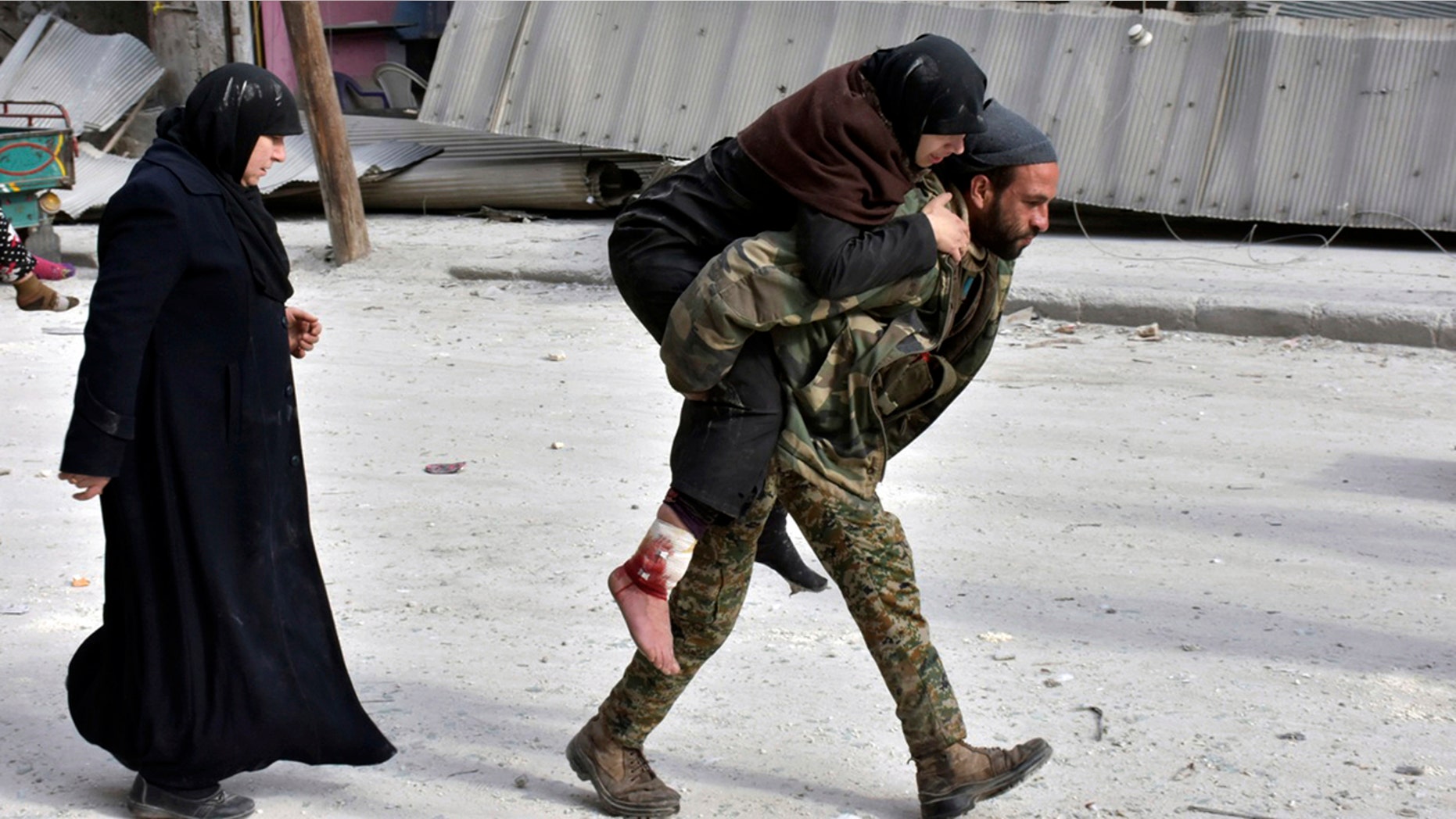 Dec. 12, 2016: In this photo released by the Syrian official news agency SANA, a Syrian soldier carries a wounded woman in eastern Aleppo.