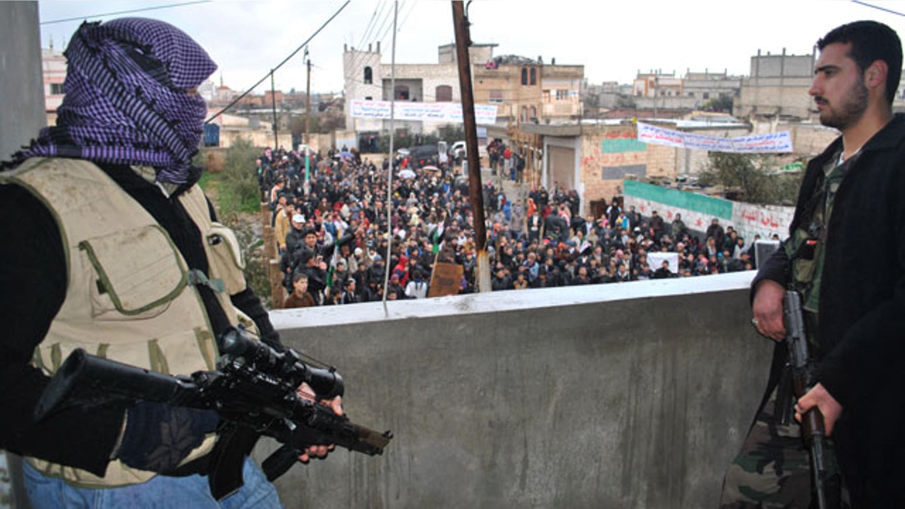 Jan. 27, 2012: Syrian army defectors stand guard on a rooftop to secure an anti-Syrian regime protest in the Deir Baghlaba area in Homs province, central Syria.