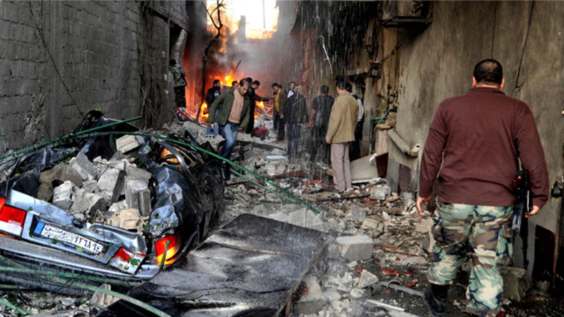 Nov. 28, 2012: A Syrian soldier, right, and citizens gather at an alley that was destroyed by two cars bombs in a suburb of Damascus, Syria.