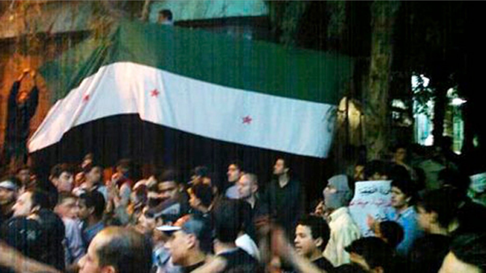 April 10, 2012: In this image provided by the Local Coordination Committees in Syria, Syrians hold the Syrian revolutionary flag aloft during a demonstration in Damascus, Syria.