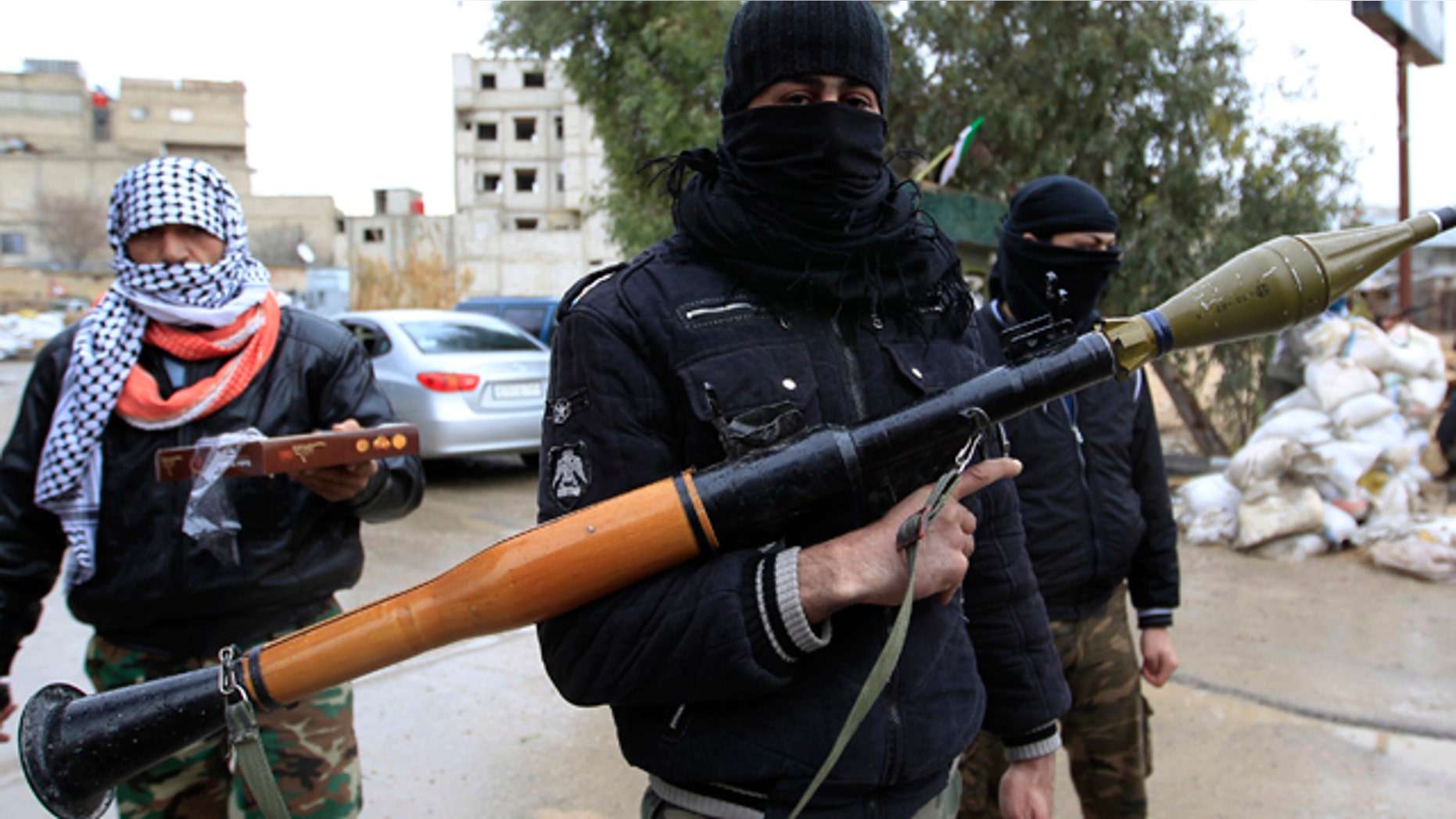 Jan. 27: Syrian soldiers, who have defected to join the Free Syrian Army, look on as one holds up an RPG and another delivers sweets in Saqba, in Damascus suburbs.
