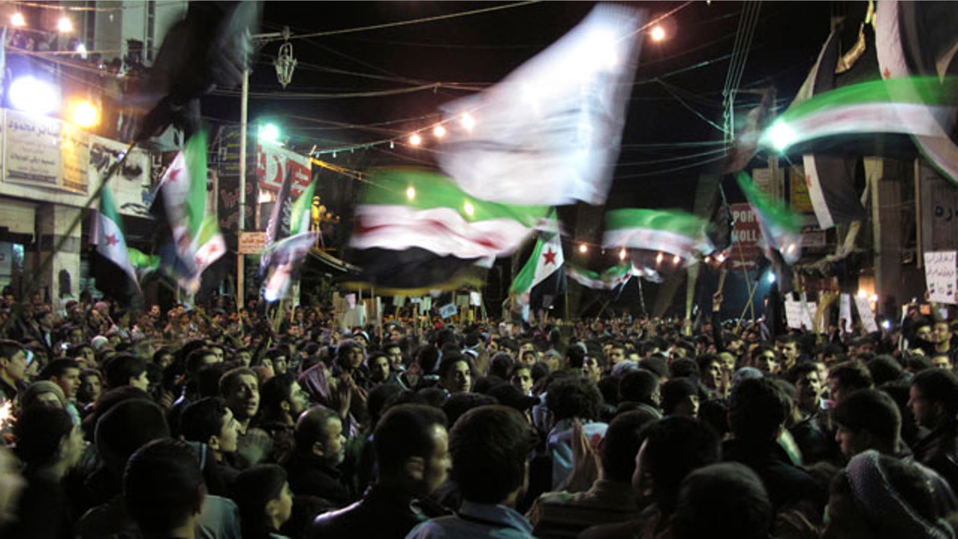 April 2, 2012: Syrians wave revolutionary flags and chant slogans at a night protest against President Bashar Assad in a neighborhood of Damascus, Syria.