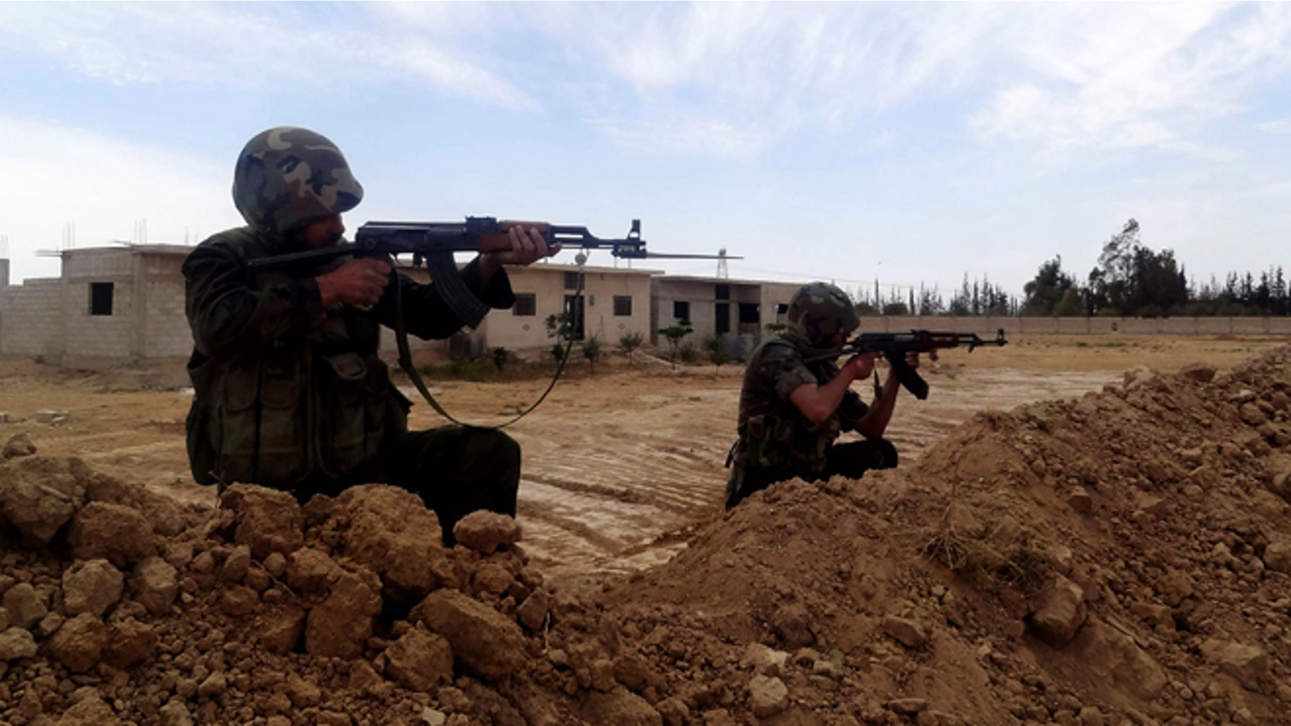 April 24, 2013: This photo released by the Syrian official news agency SANA, shows two Syrian Army soldiers aiming their weapons, in Otaybah town, east of Damascus, Syria. After five weeks of battle, Syrian government troops captured a strategic town near Damascus, cutting an arms route for rebels trying to topple President Bashar Assad's regime, state media and activists said Thursday.